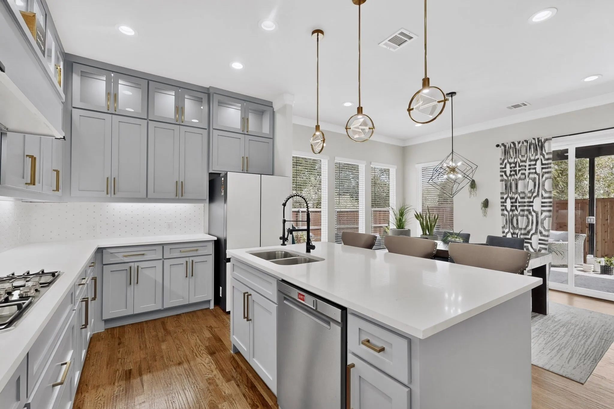 Spacious kitchen featuring an island, light gray cabinetry, white countertops, stainless steel appliances, and wood-finish flooring