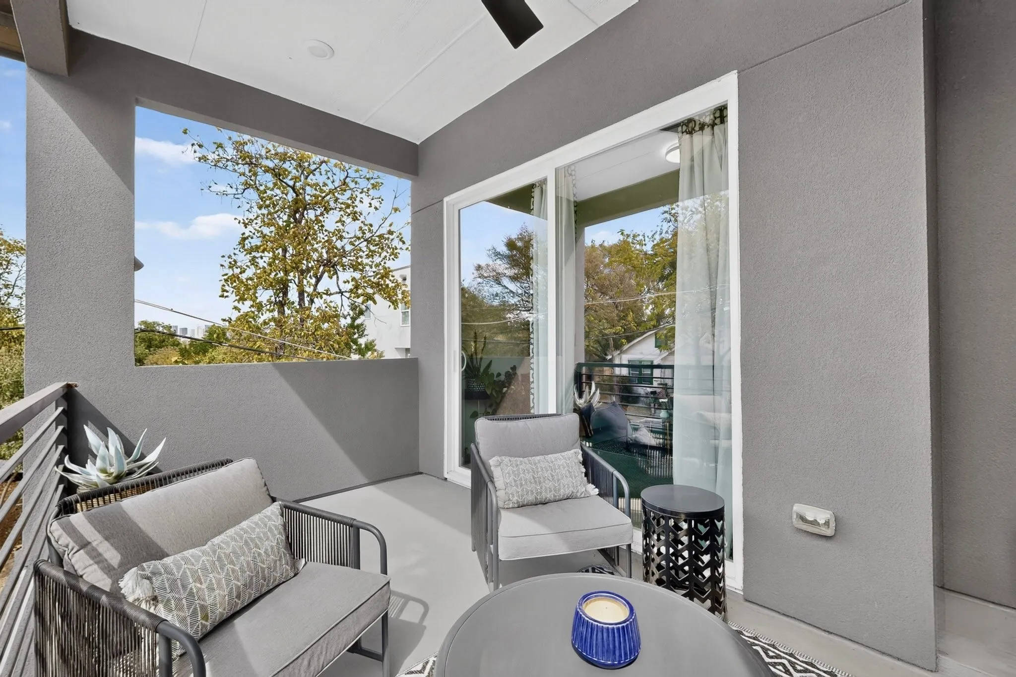 Balcony featuring a ceiling fan, sliding glass doors, metal railings, and a smooth stucco finish