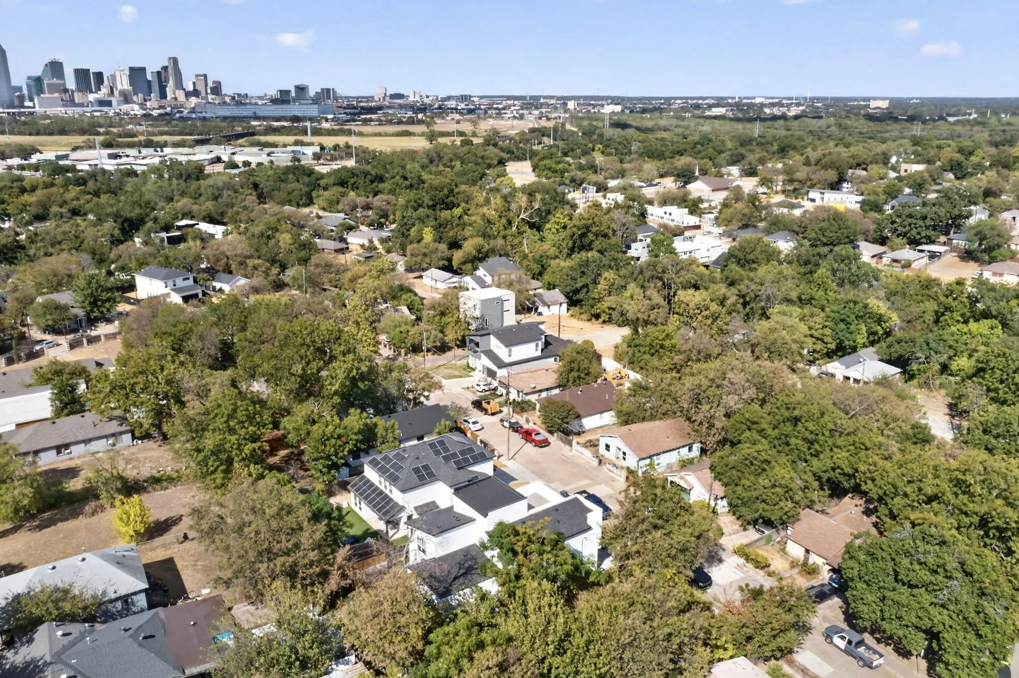 Residential neighborhood with mature trees and a distant city skyline