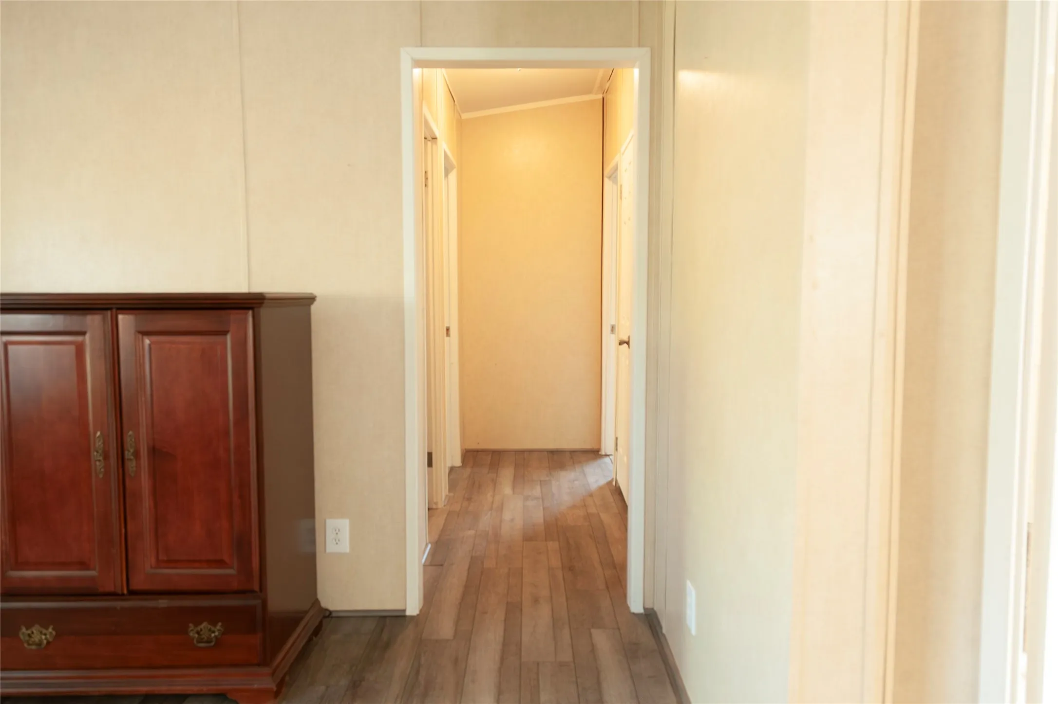 Hallway featuring wood-finish flooring, light-toned walls, and white trim