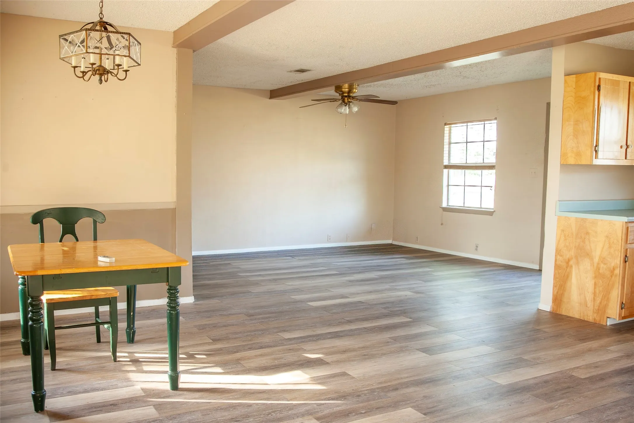 Open-concept living space with wood-finish flooring throughout, a ceiling fan, and large window