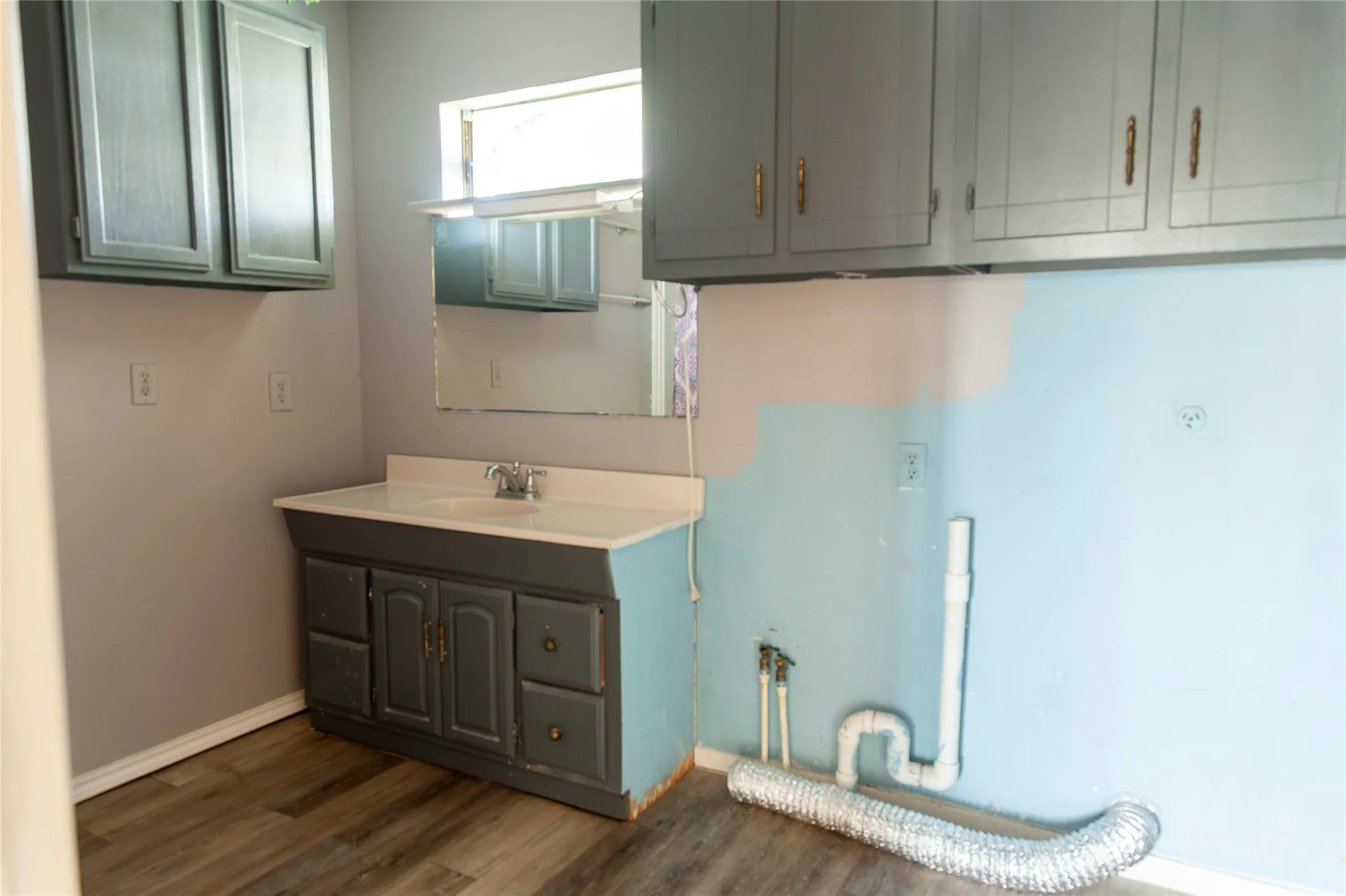 Bathroom vanity featuring an integrated sink, chrome faucet, and gray cabinetry with brass-tone hardware