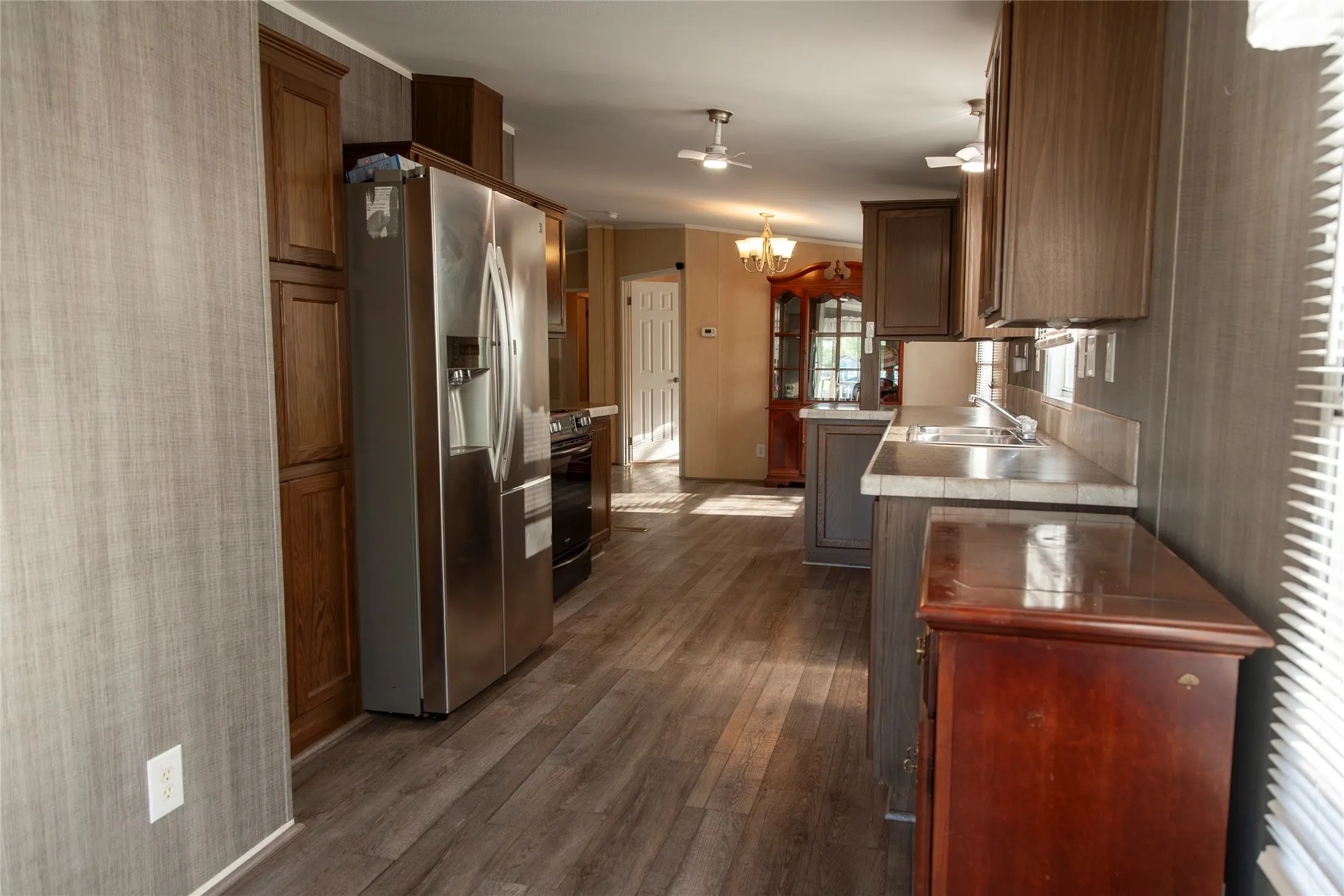 Galley kitchen featuring wood-finish flooring, stainless steel appliances, extensive cabinetry, and a countertop with an integrated sink