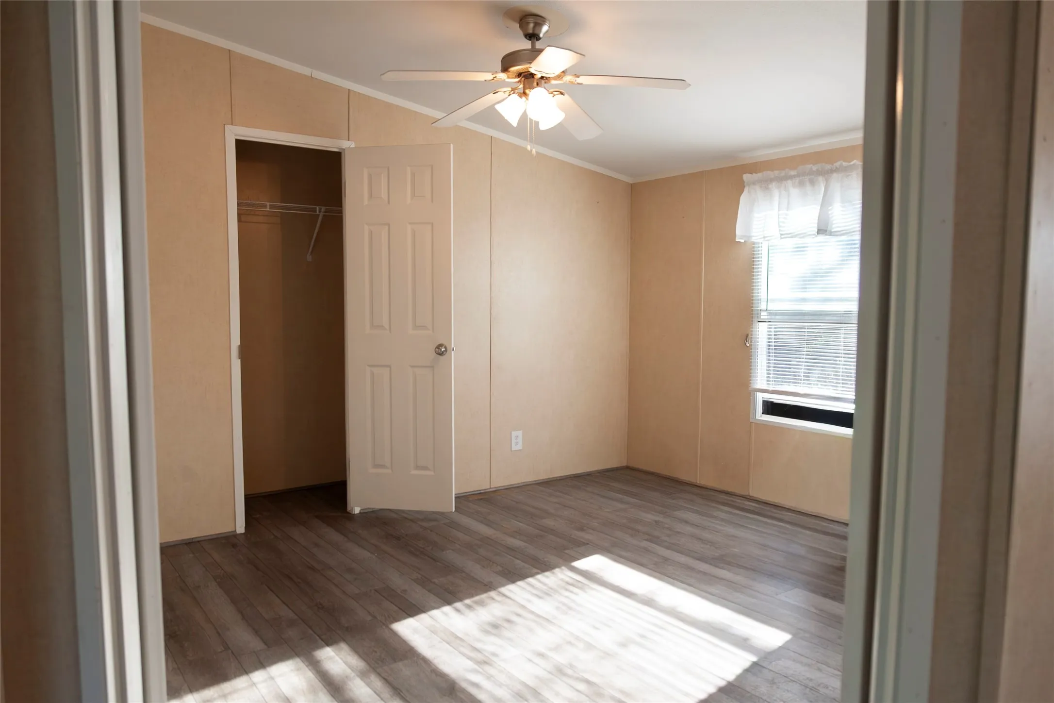Bedroom featuring wood-finish flooring, a ceiling fan with integrated lighting, and a closet with a wire shelving system