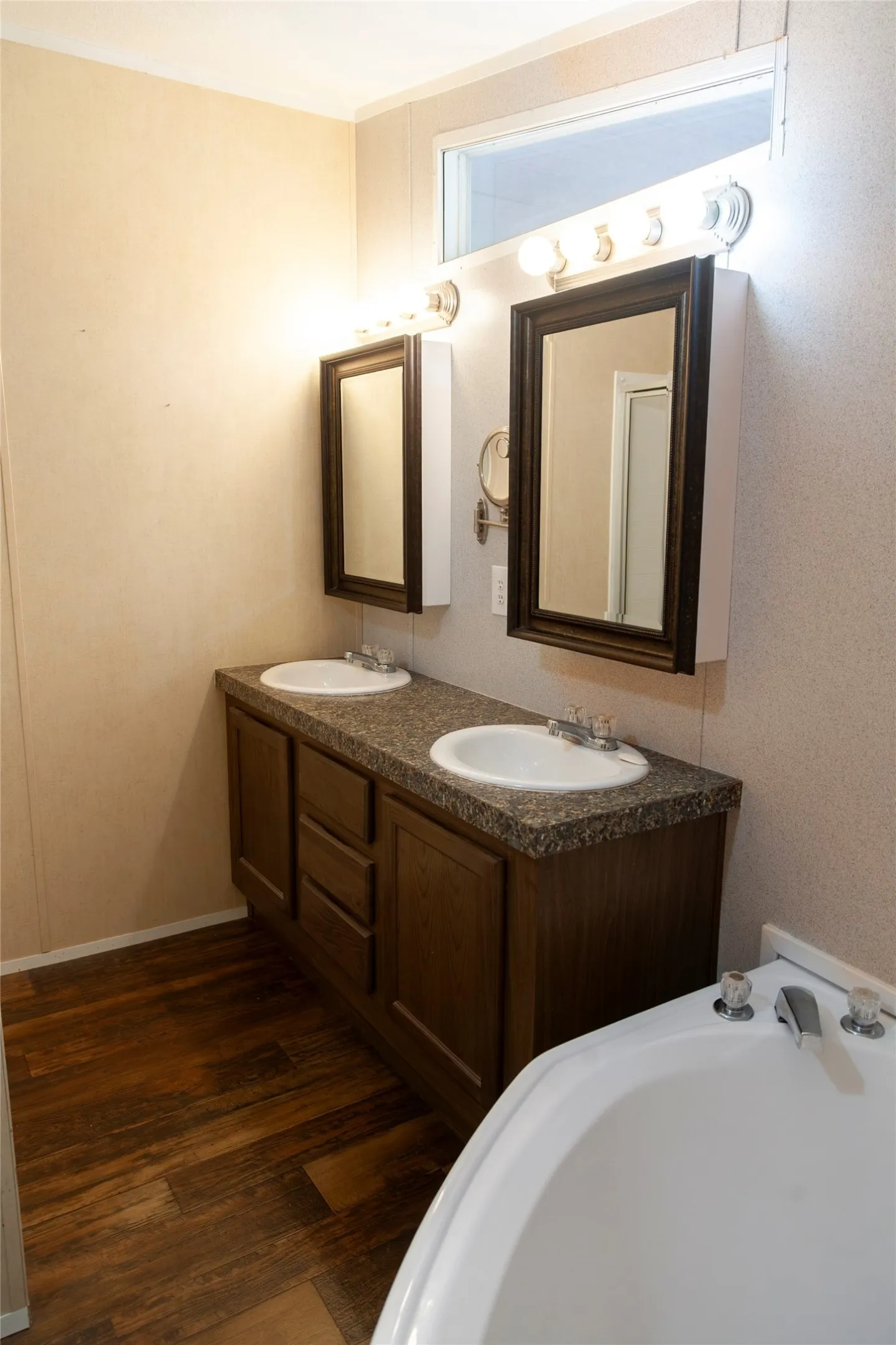 Bathroom featuring a dual vanity with a speckled countertop, integrated sinks, and wood-finish cabinetry