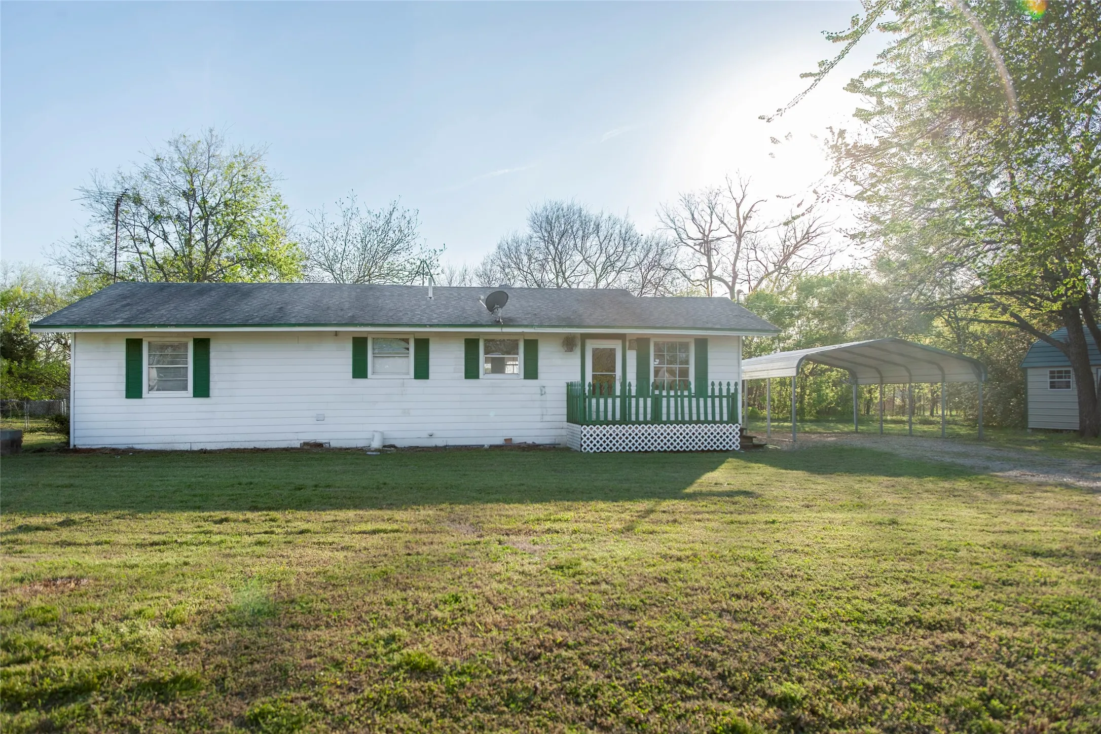 Single-story white residence featuring green shutters and a front porch with green railings