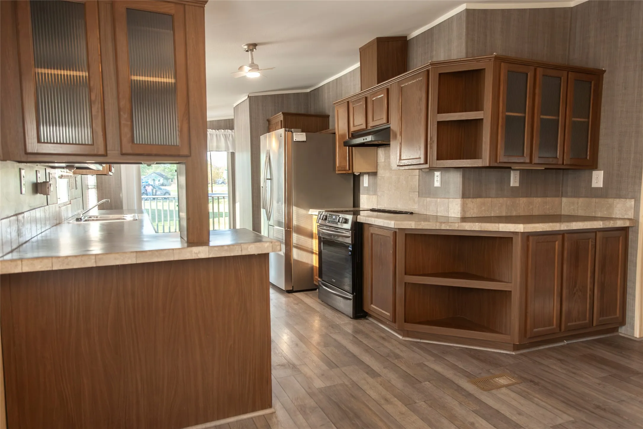 Kitchen featuring wood-finish cabinetry, stainless steel appliances, and a tiled backsplash