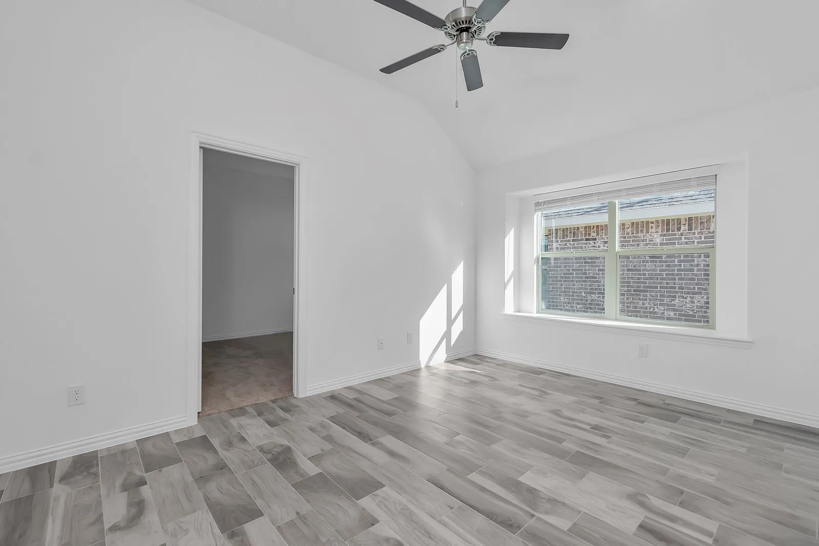 Empty room featuring vaulted ceiling and a ceiling fan