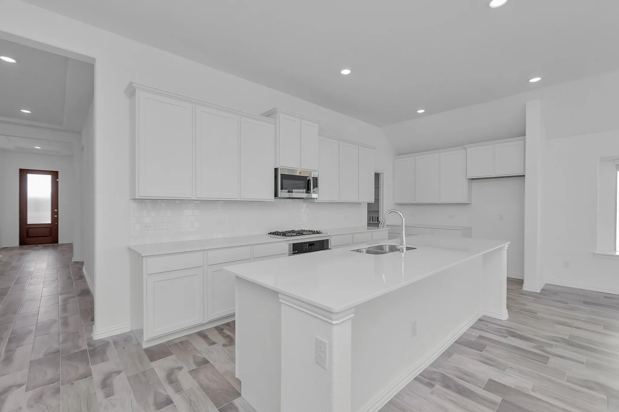 Kitchen featuring stainless steel appliances, white cabinetry, a center island with sink, tasteful backsplash, and recessed lighting