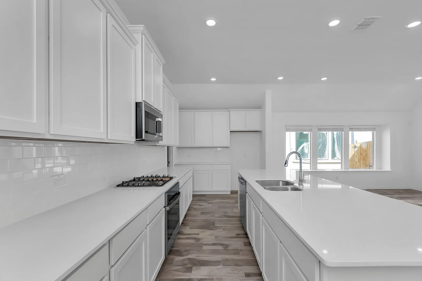 Kitchen with stainless steel appliances, recessed lighting, decorative backsplash, white cabinetry, and light countertops
