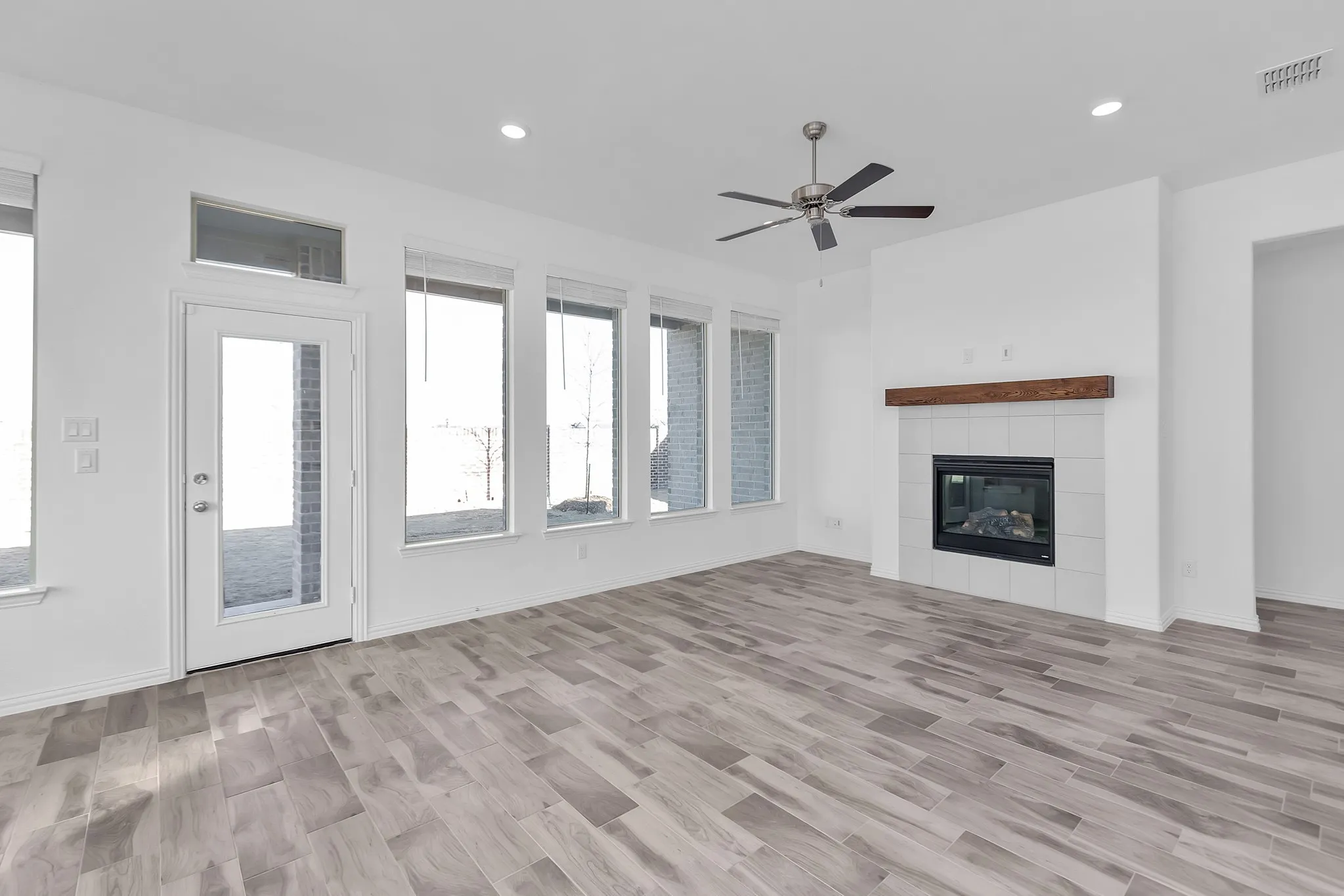 Unfurnished living room with ceiling fan, recessed lighting, a tile fireplace, and light wood-style floors