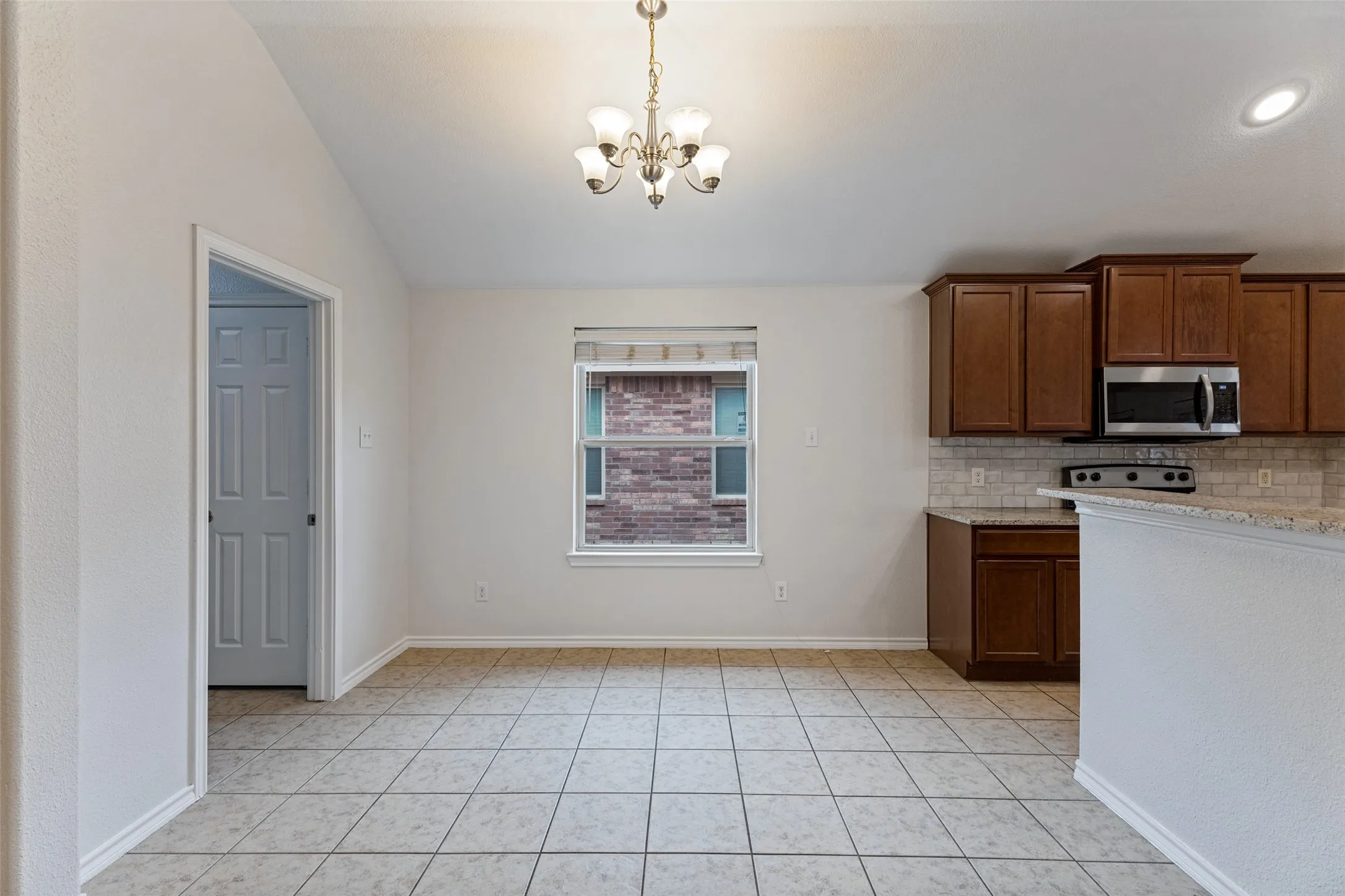 Spacious kitchen featuring wood-finish cabinetry, stainless steel appliances, and tile countertops with coordinating backsplash