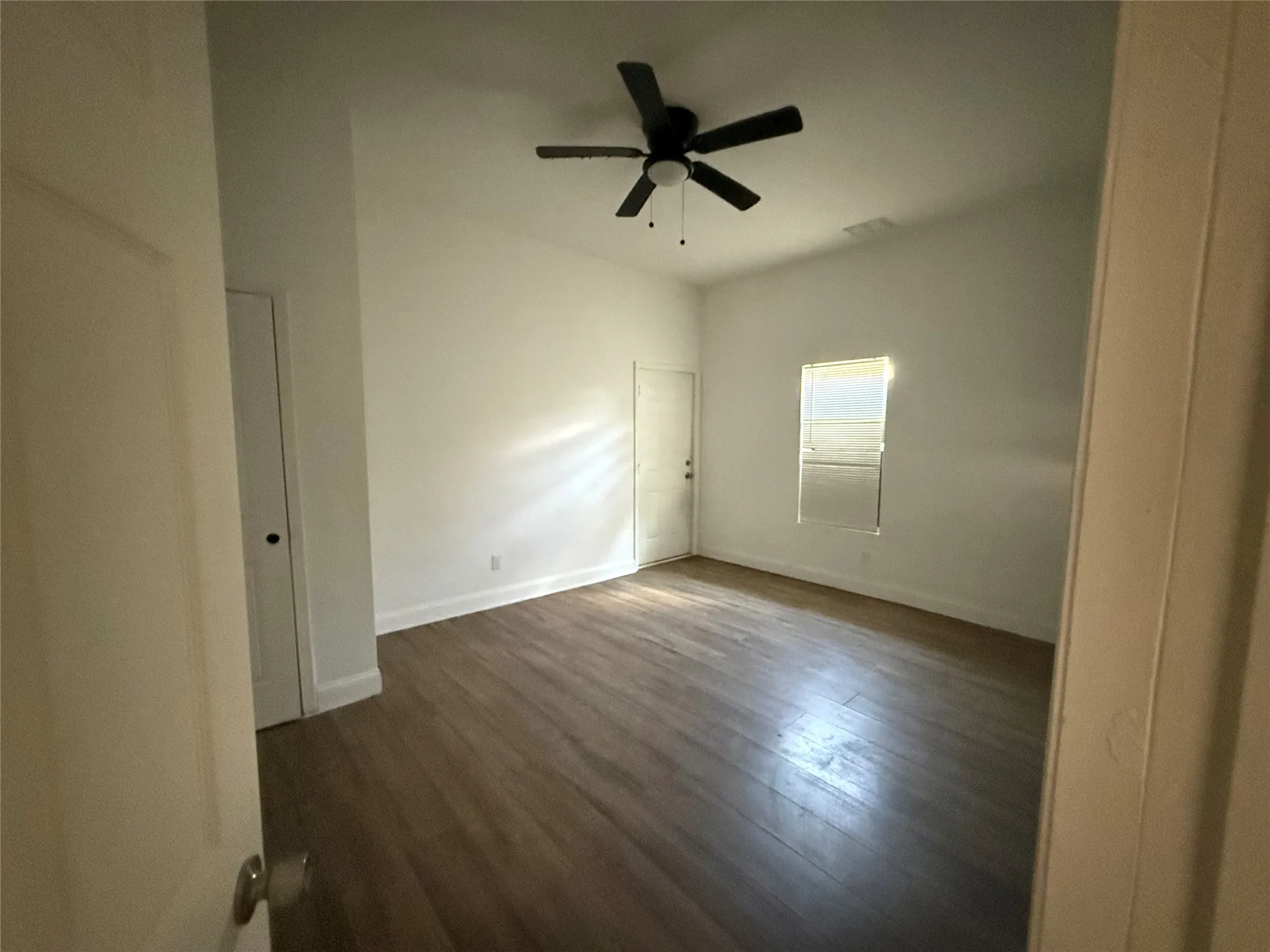 Vaulted ceiling with a ceiling fan, wood-finish flooring, and a single window