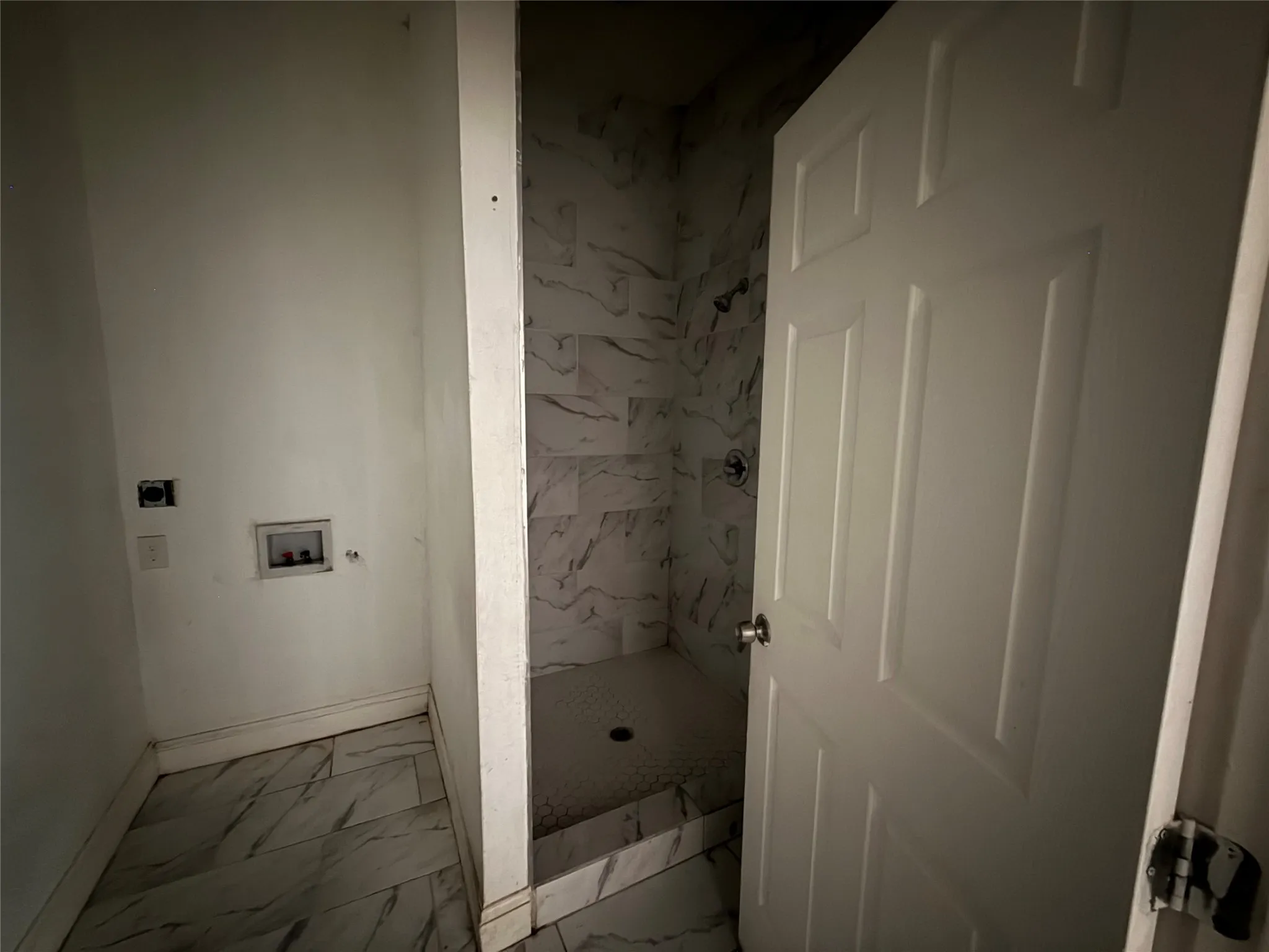 Tiled flooring throughout, wall-mounted shower fixture, and a paneled interior door