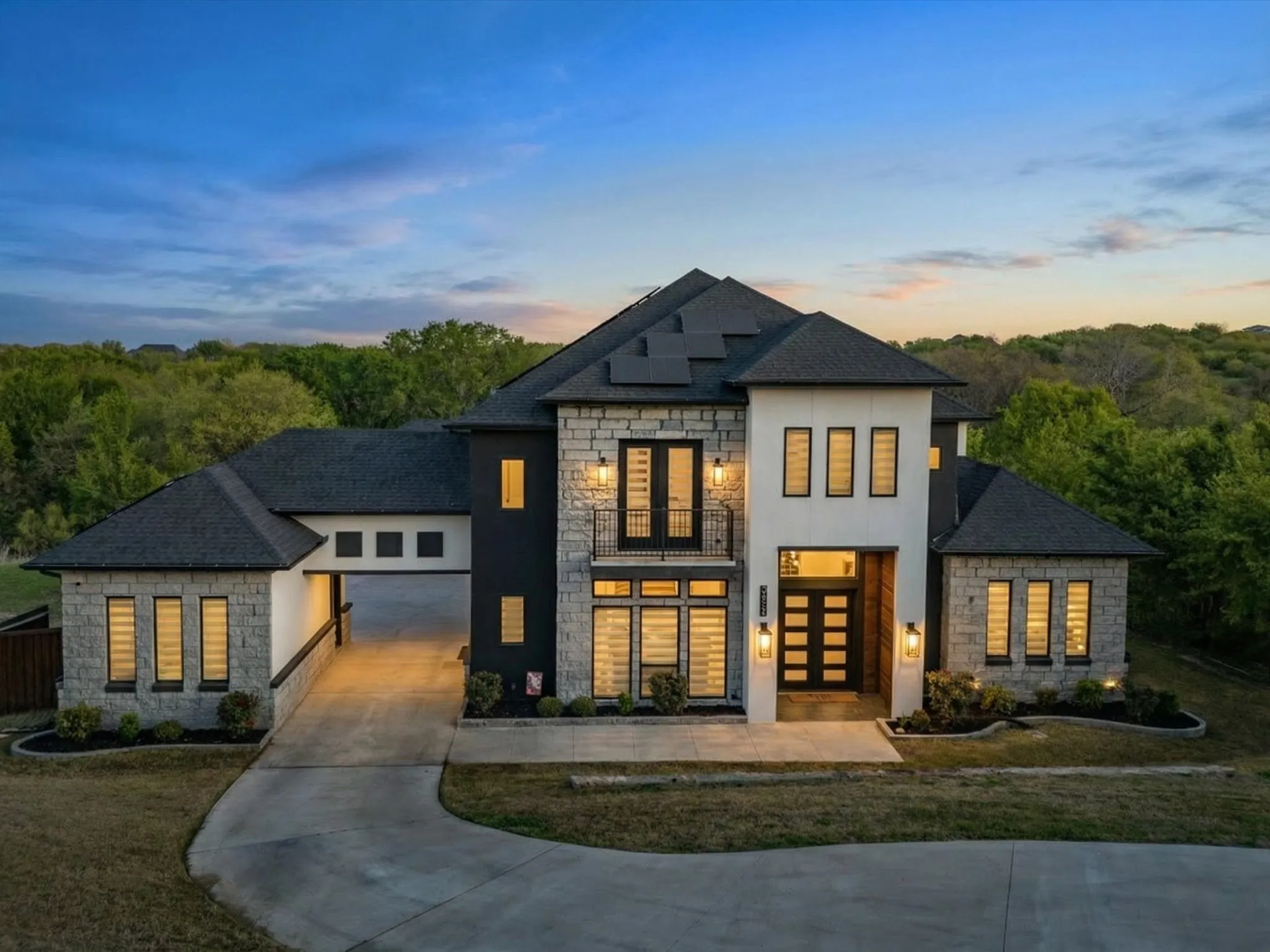 Front of property featuring stone siding, french doors, roof mounted solar panels, stucco siding, and concrete driveway