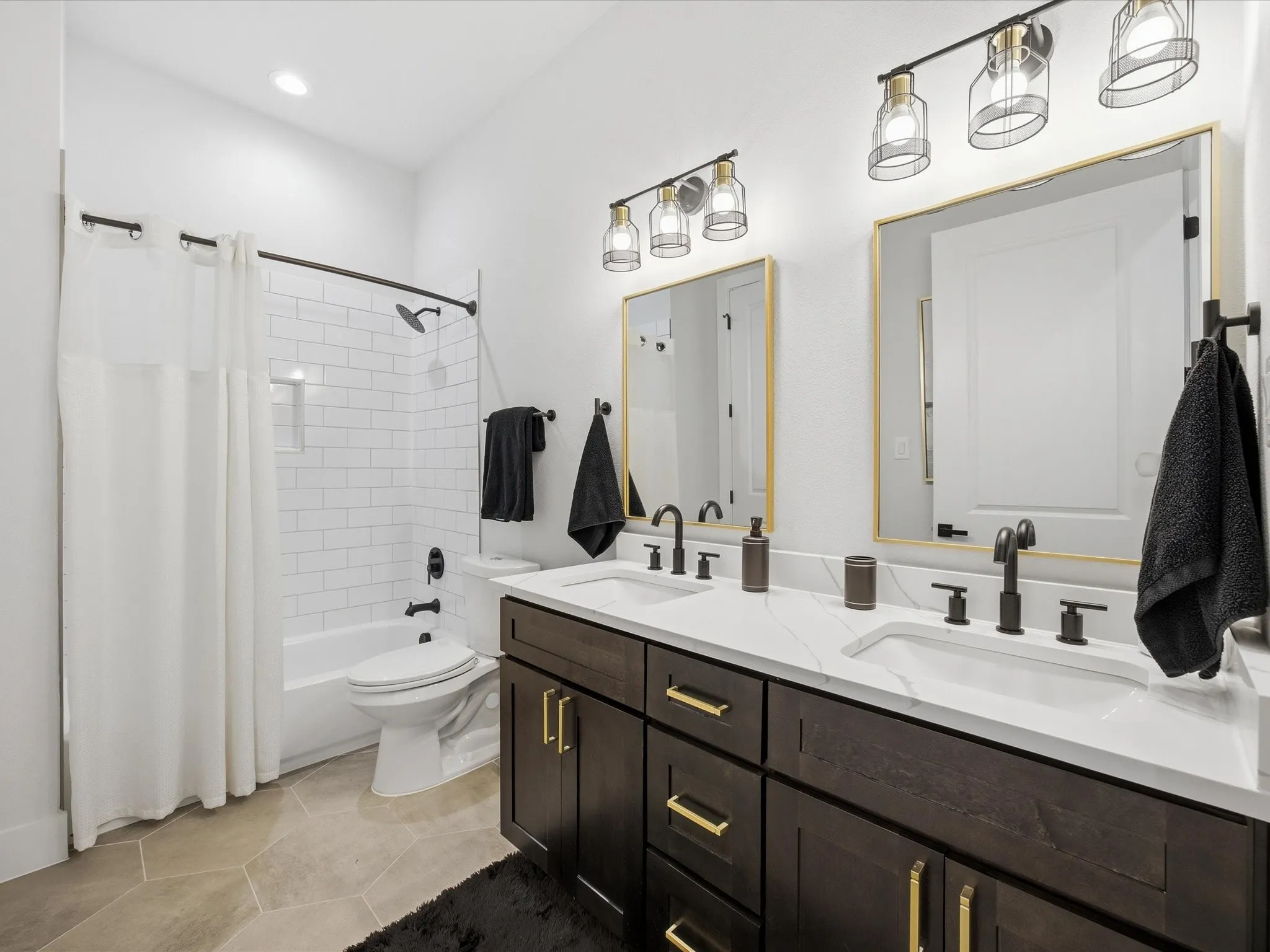 Bathroom featuring double vanity, light tile patterned floors, and shower / bath combo