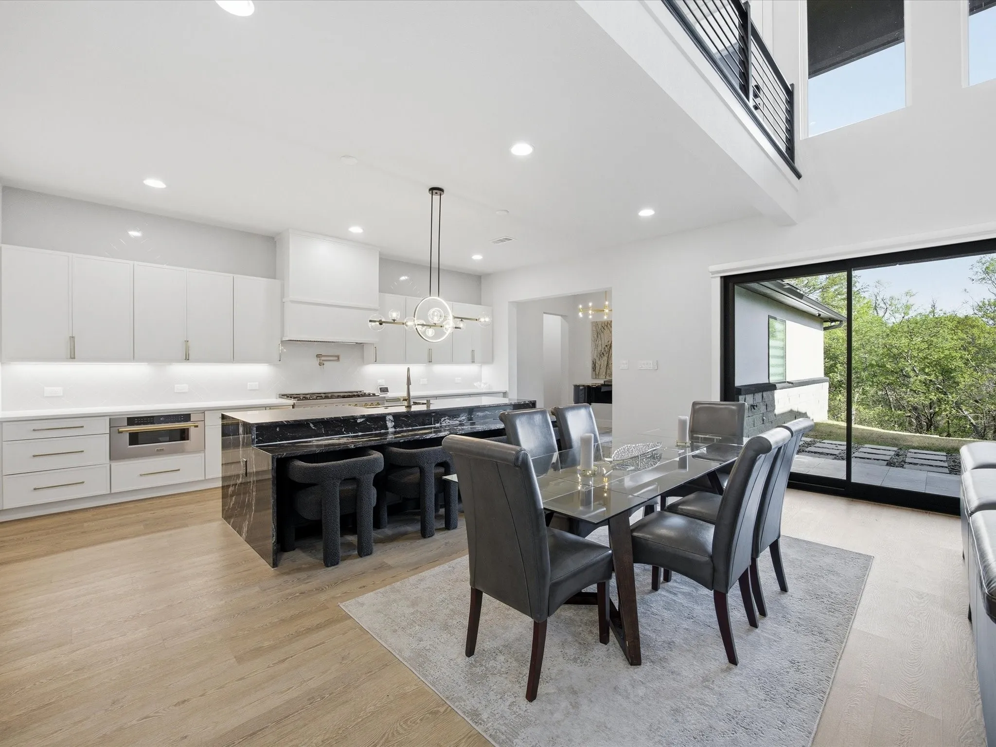 Dining area with suspended lighting, light wood-style floors, and a high ceiling