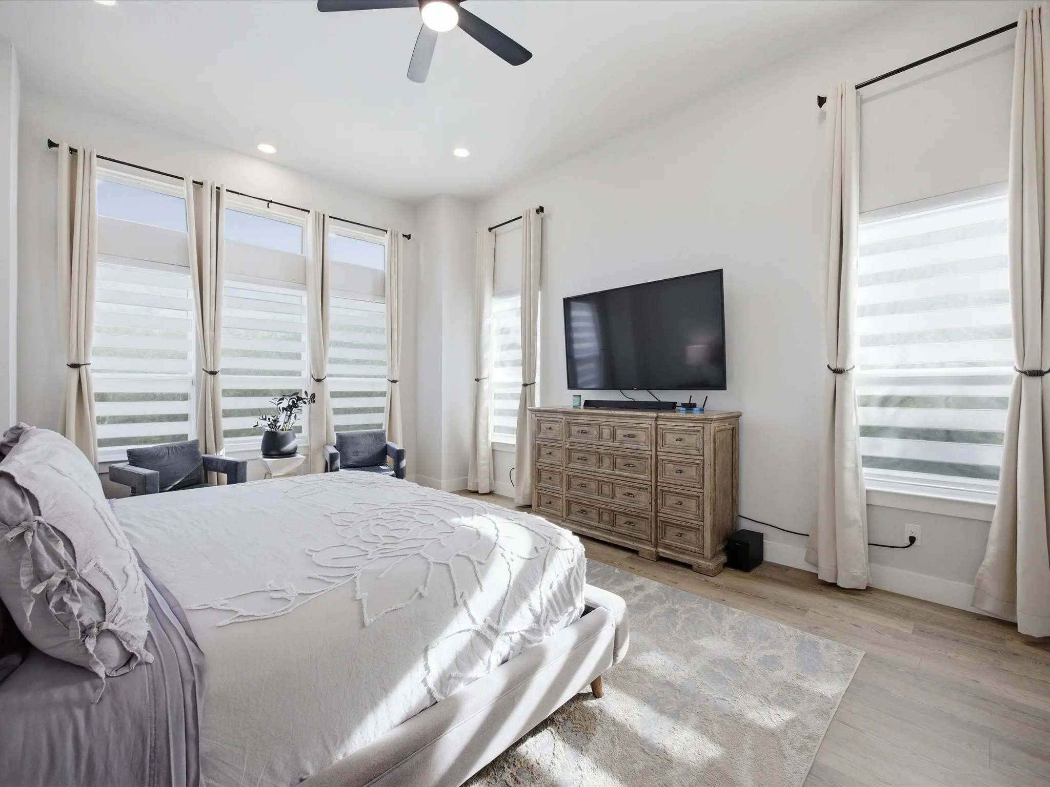 Bedroom featuring multiple windows, ceiling fan, light wood-style flooring, and recessed lighting