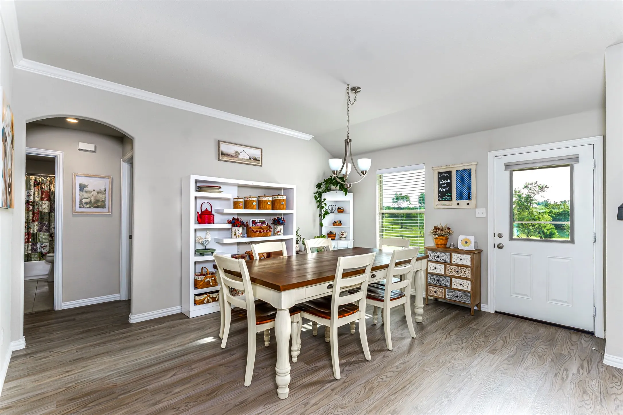 Wood-finish flooring, white crown molding, arched entryway, and a built-in shelving unit
