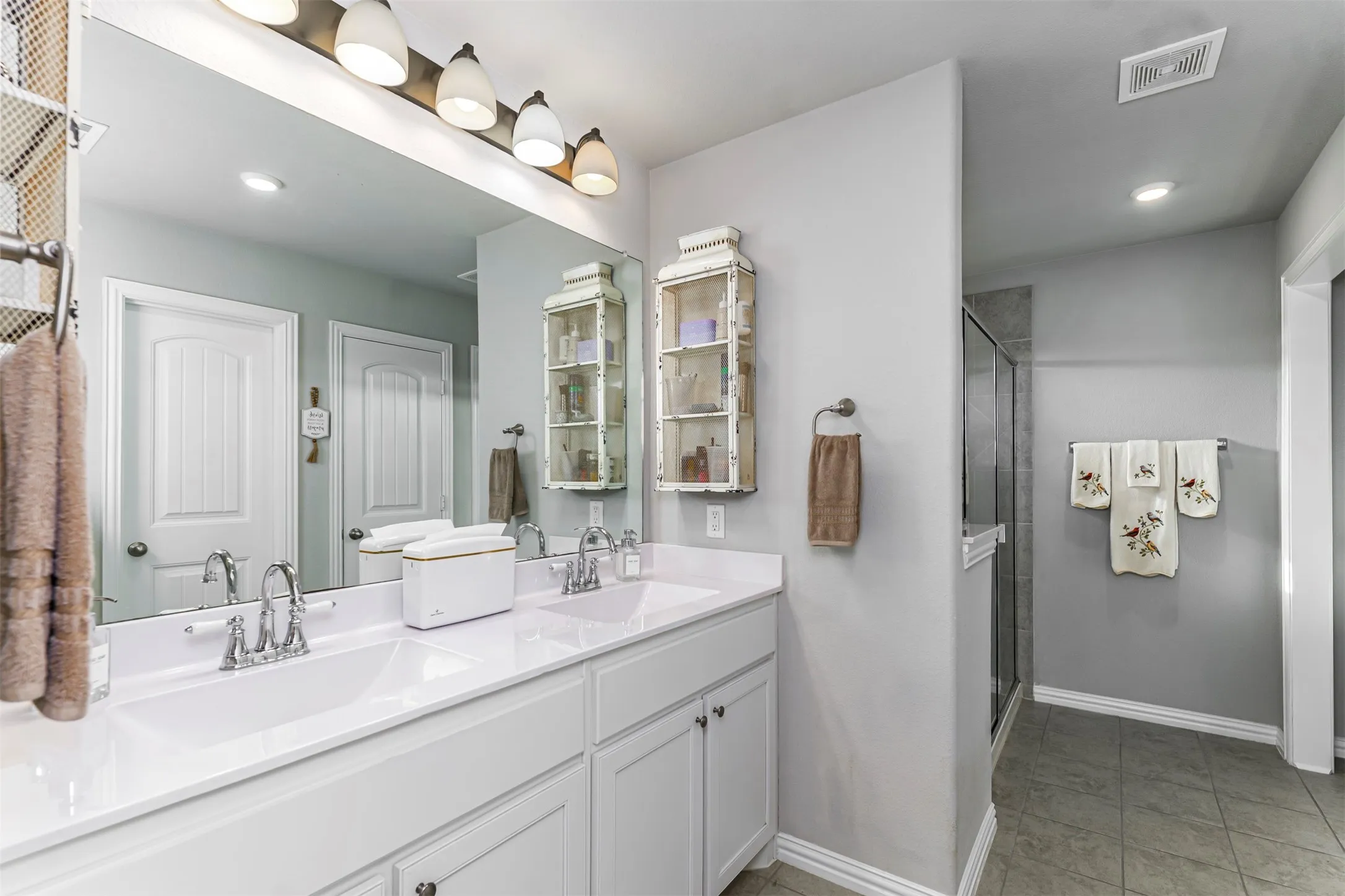 Dual vanity with white cabinetry and chrome fixtures, illuminated by a multi-bulb light bar