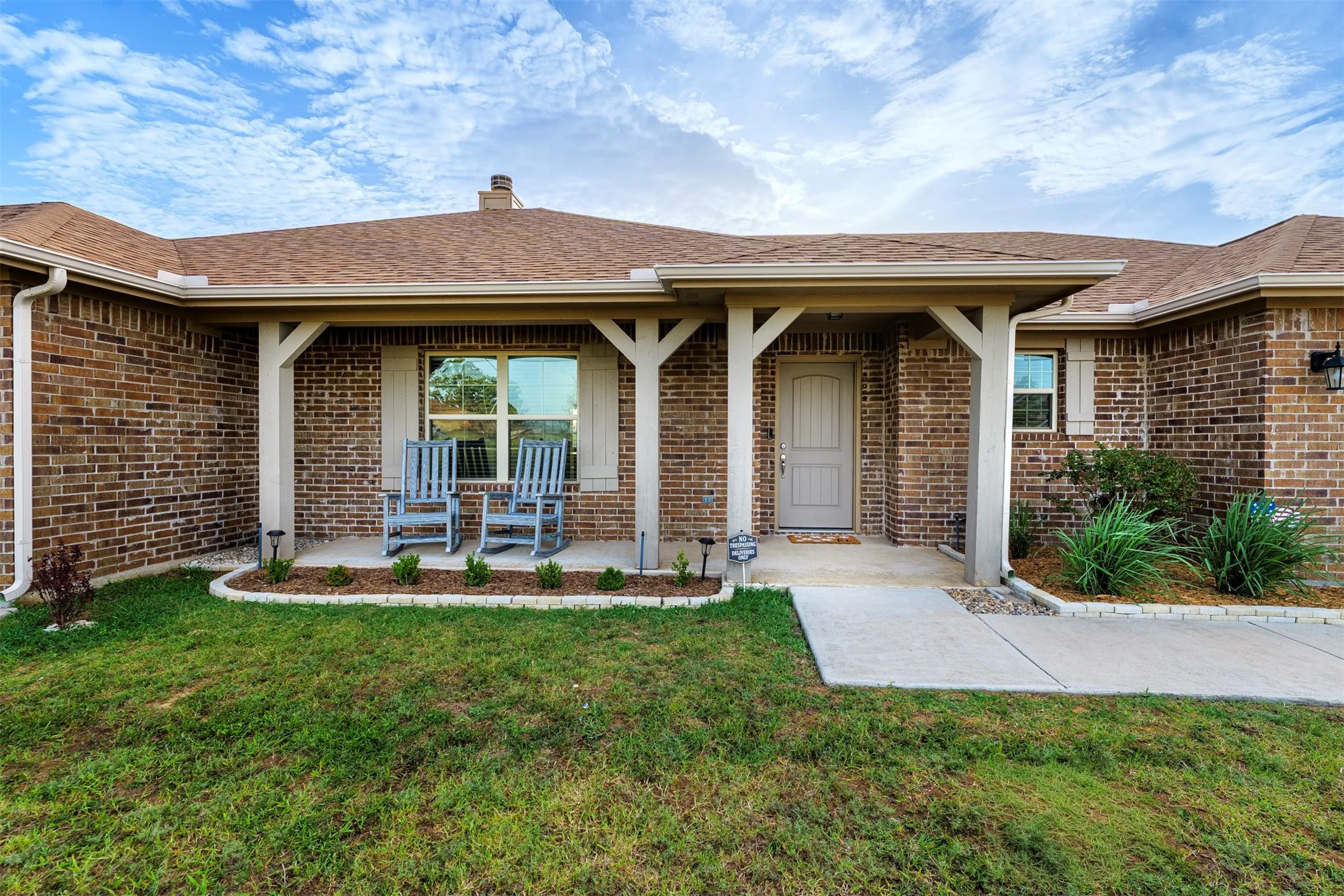 Brick exterior with a covered entry, wood-finish support columns, and a concrete walkway