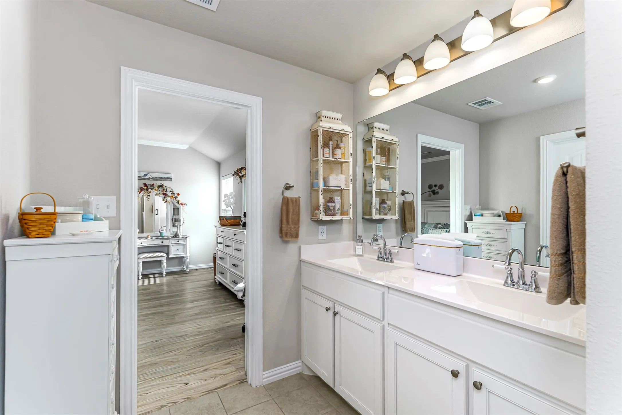 Dual vanity with white cabinetry, polished chrome fixtures, and a large integrated mirror