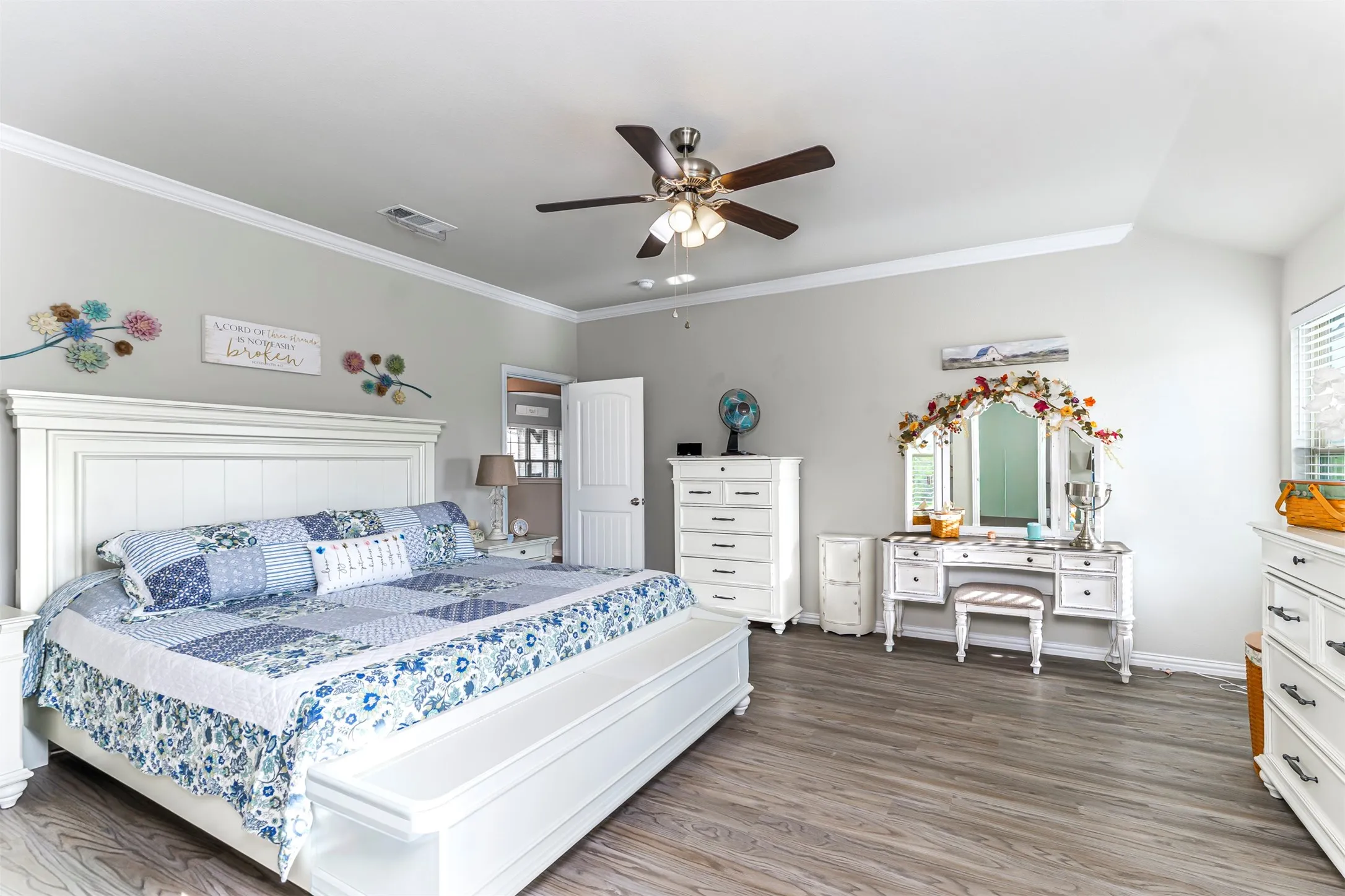 Wood-finish flooring with crown molding and a ceiling fan with integrated lighting