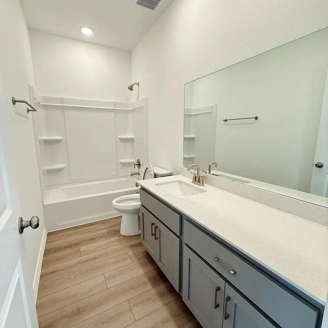 Wood-finish flooring with a vanity featuring a light-colored countertop and a rectangular undermount sink