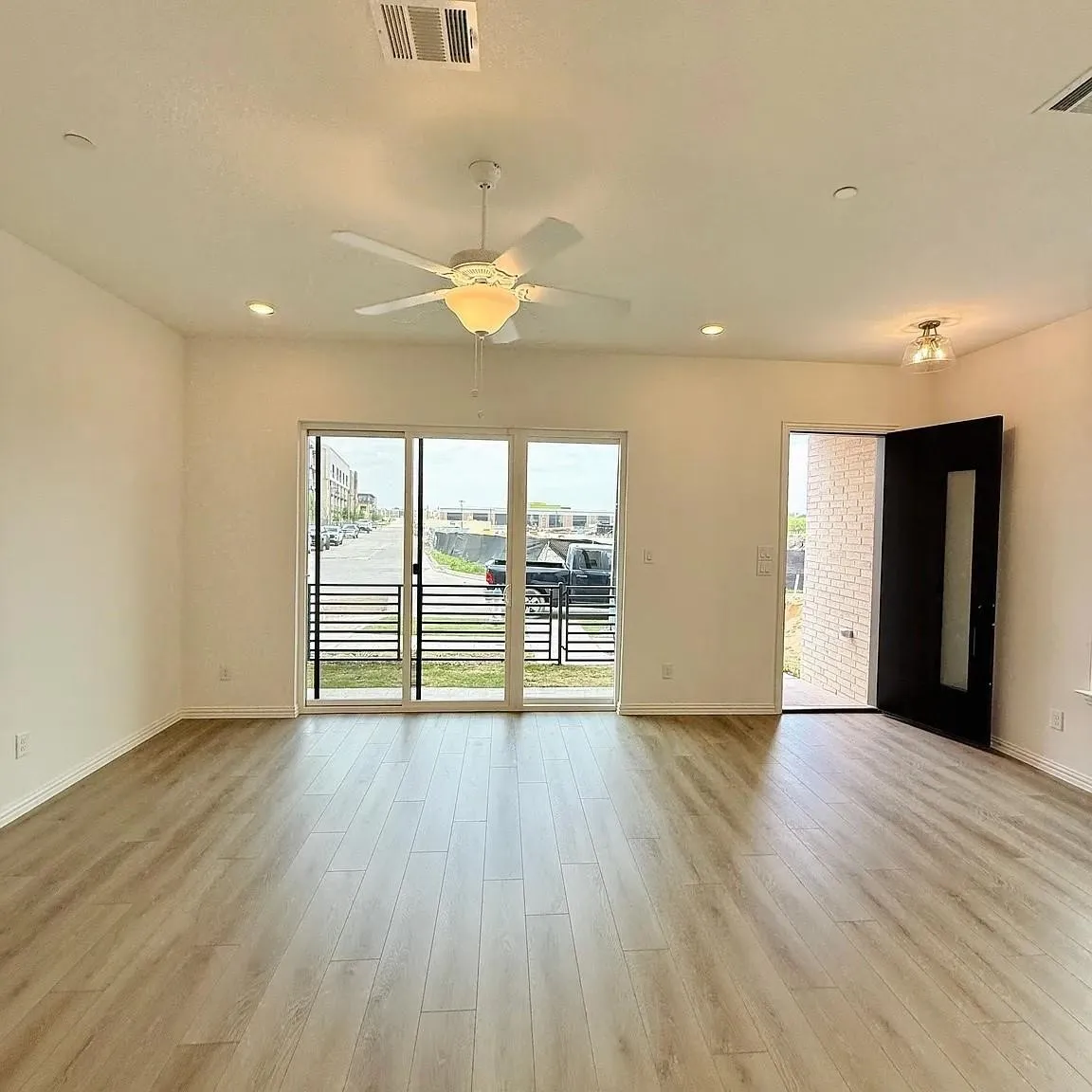 Wood-finish flooring, recessed lighting, ceiling fan, sliding glass door, and solid entry door