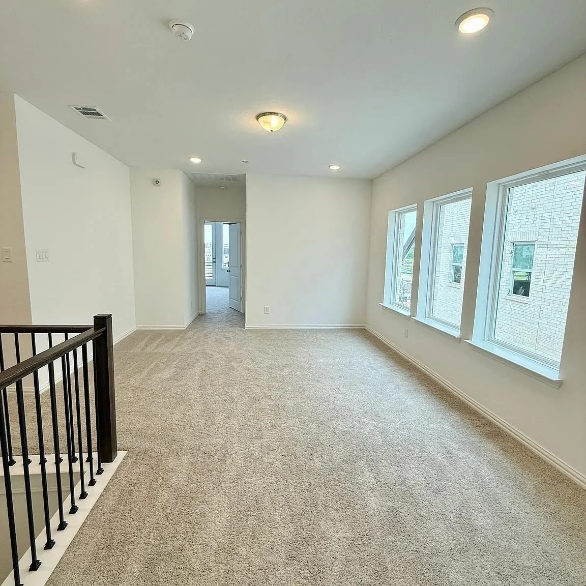 Carpeted open-concept room with multiple windows, recessed lighting, and a semi-flush mount ceiling fixture