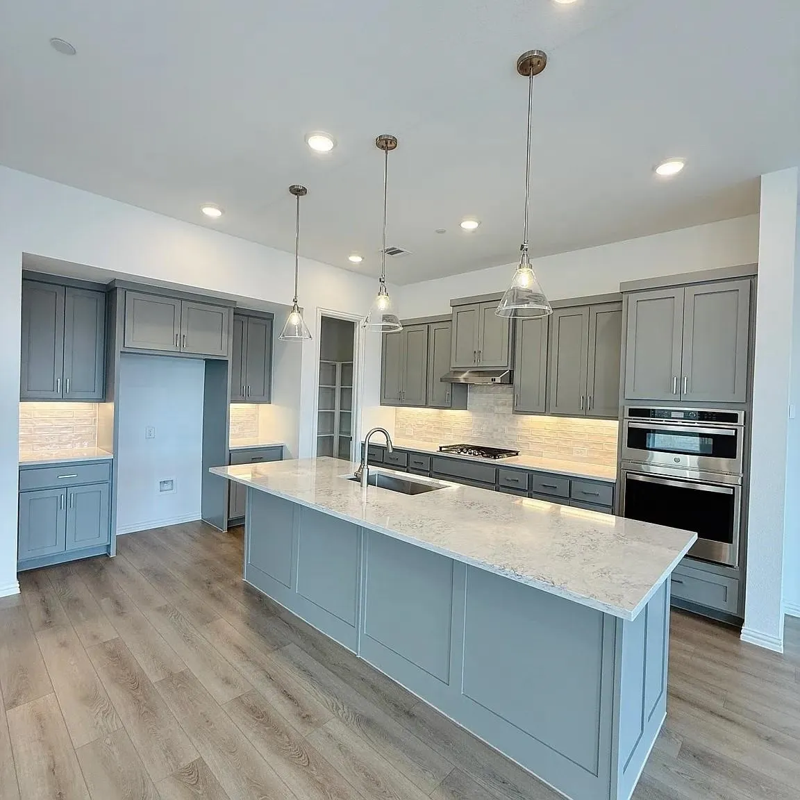 Kitchen featuring wood-finish flooring, recessed lighting, and a center island with a built-in sink