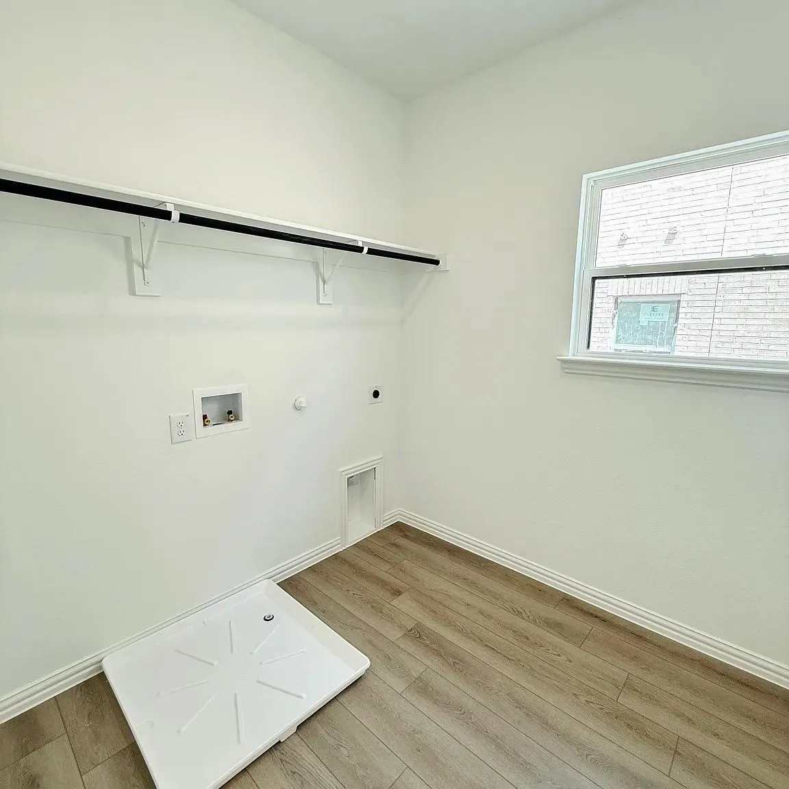 Utility room featuring wood-finish flooring, a built-in shelving unit, and a window for natural light
