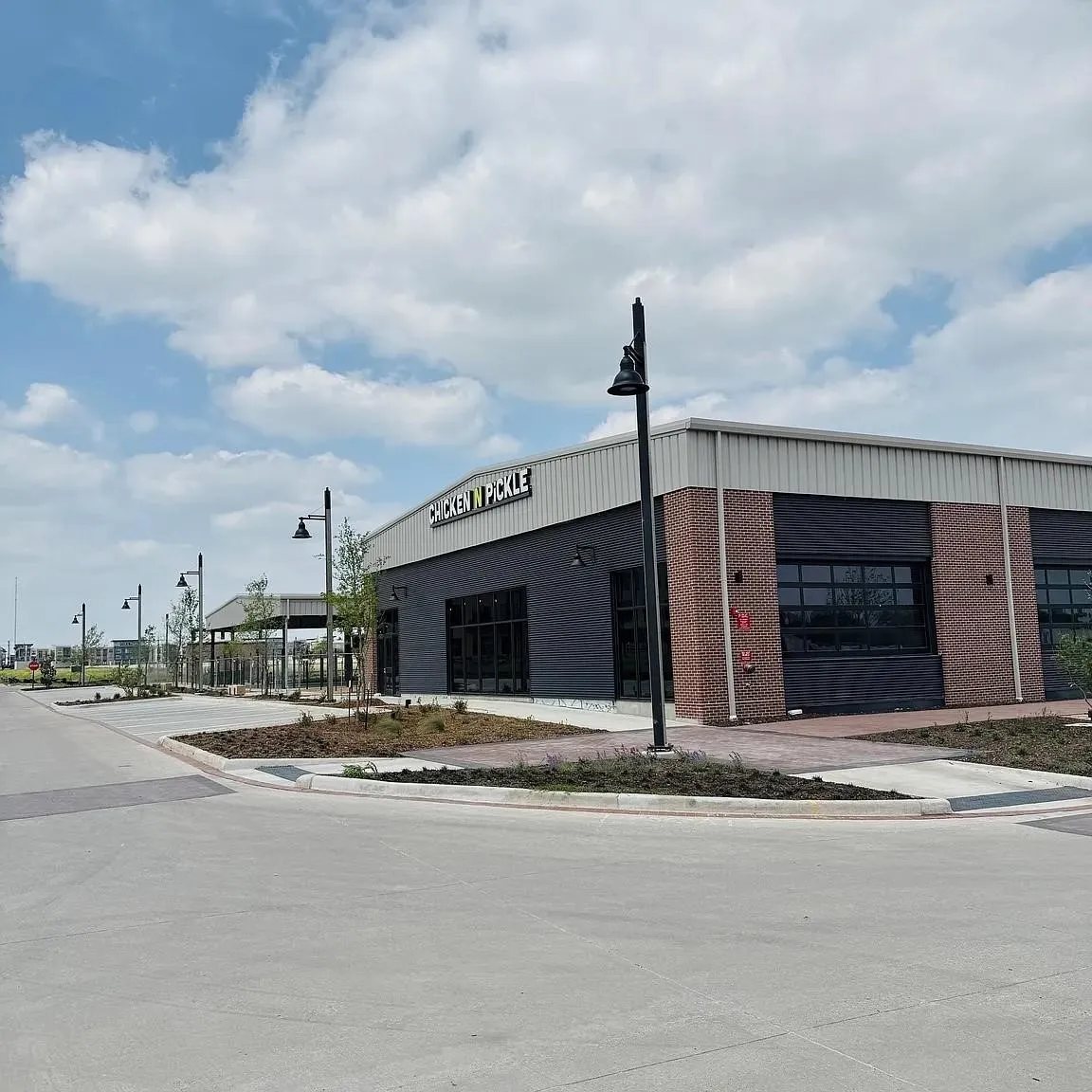 Commercial building featuring brick and dark panel siding, a light metal roof, and large storefront windows