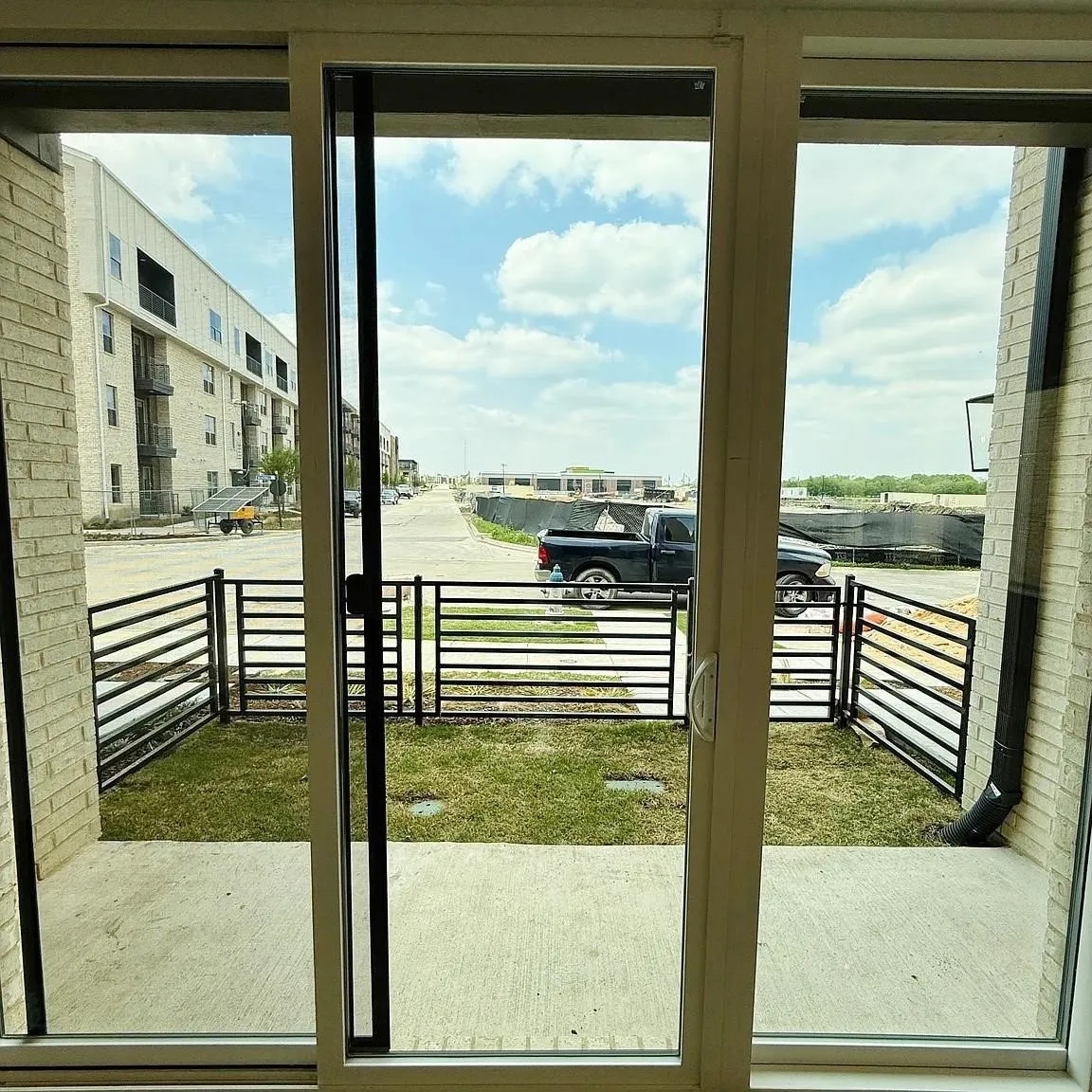 Sliding glass patio door with an exterior concrete patio, a private fenced yard with natural grass, and brick exterior construction