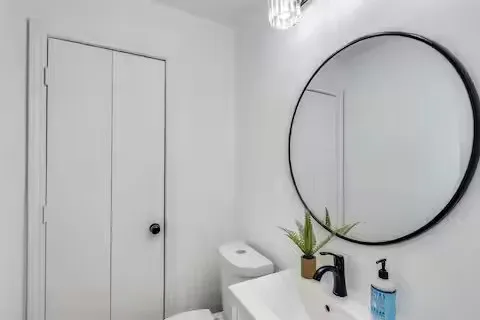 Vanity with integrated sink, matte black faucet, and circular mirror with black frame