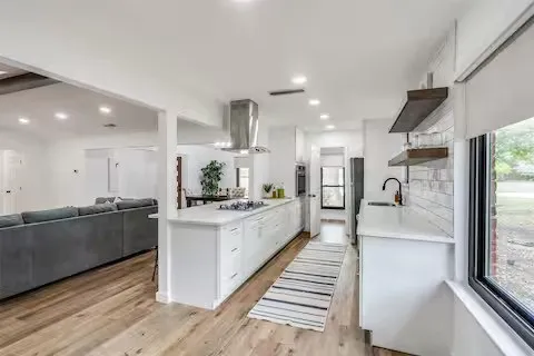 Spacious kitchen featuring an extended island, wood-finish flooring, recessed lighting, and a stainless steel range hood