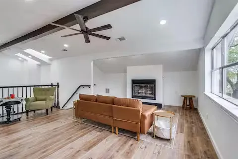 Hardwood-finish flooring, recessed lighting, ceiling fan, skylights, and a fireplace with a white surround