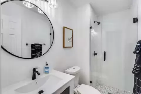 White vanity with integrated sink, matte black faucet, and round framed mirror