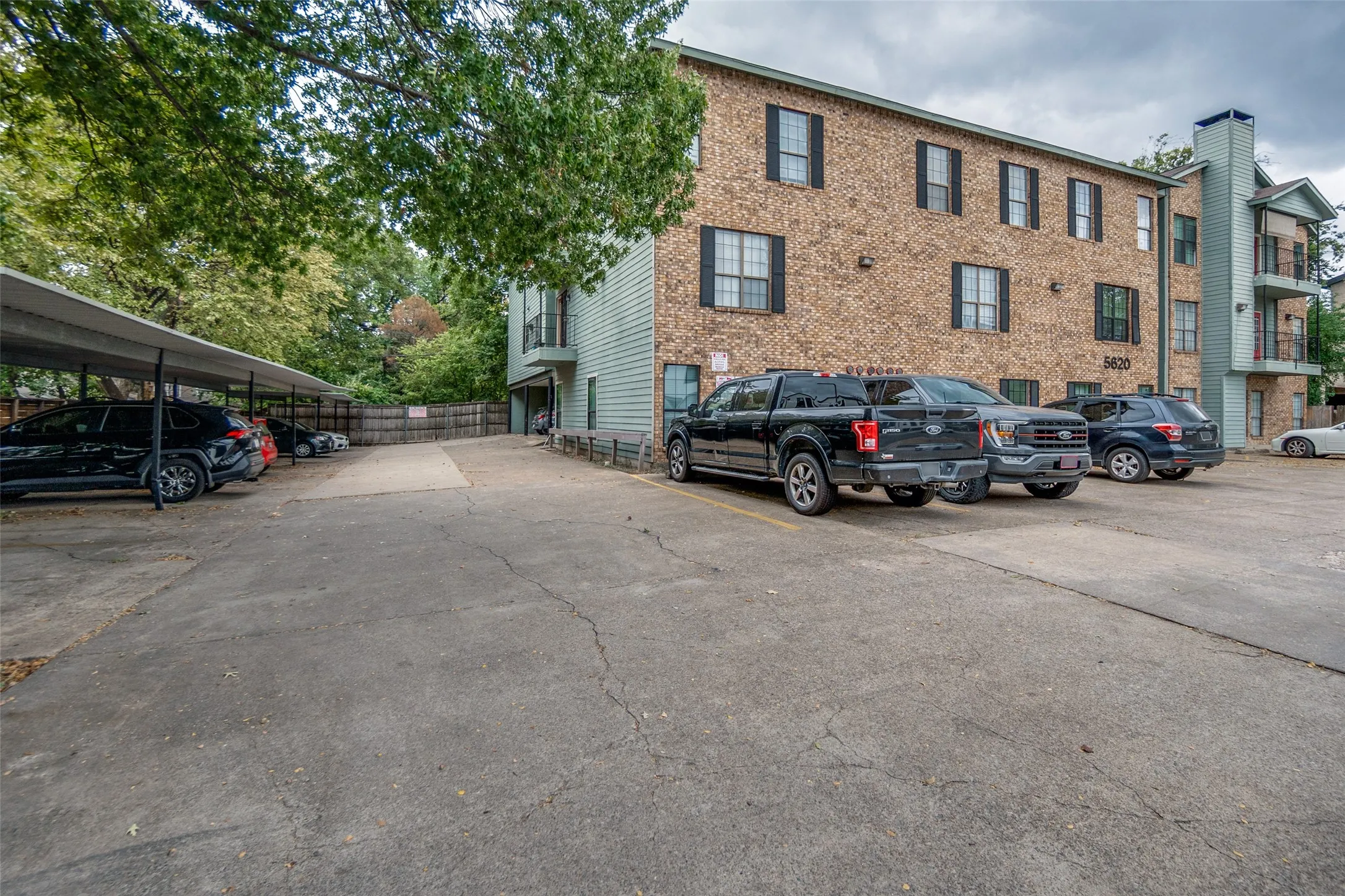 Brick facade building with multiple balconies, on-site parking, and covered parking structure