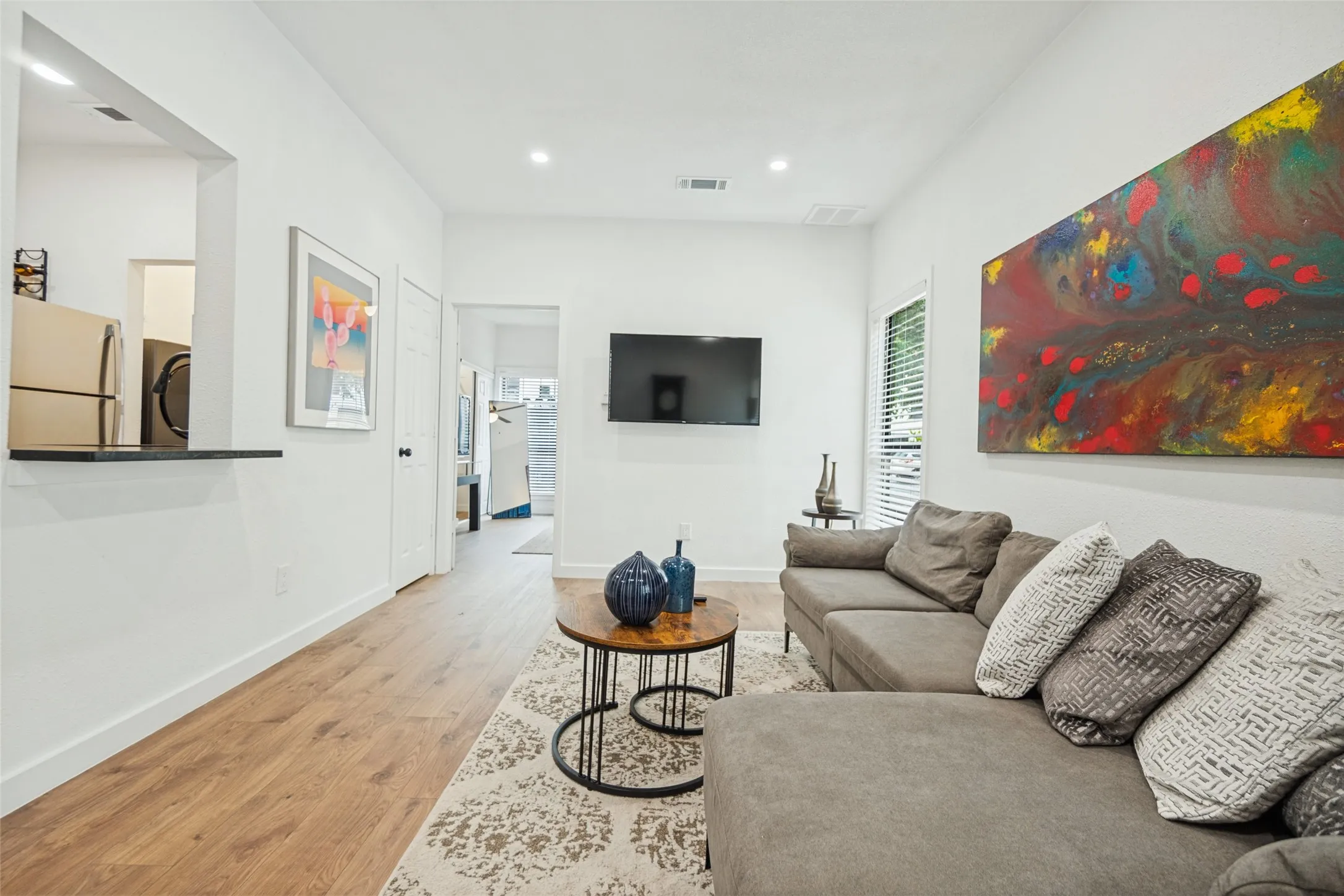 Open-concept living space with wood-finish flooring, white walls, and recessed lighting