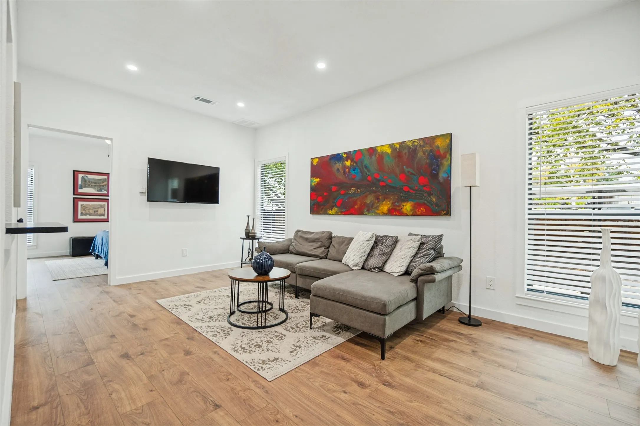 Hardwood-finish flooring, recessed lighting, and white walls with a mounted television