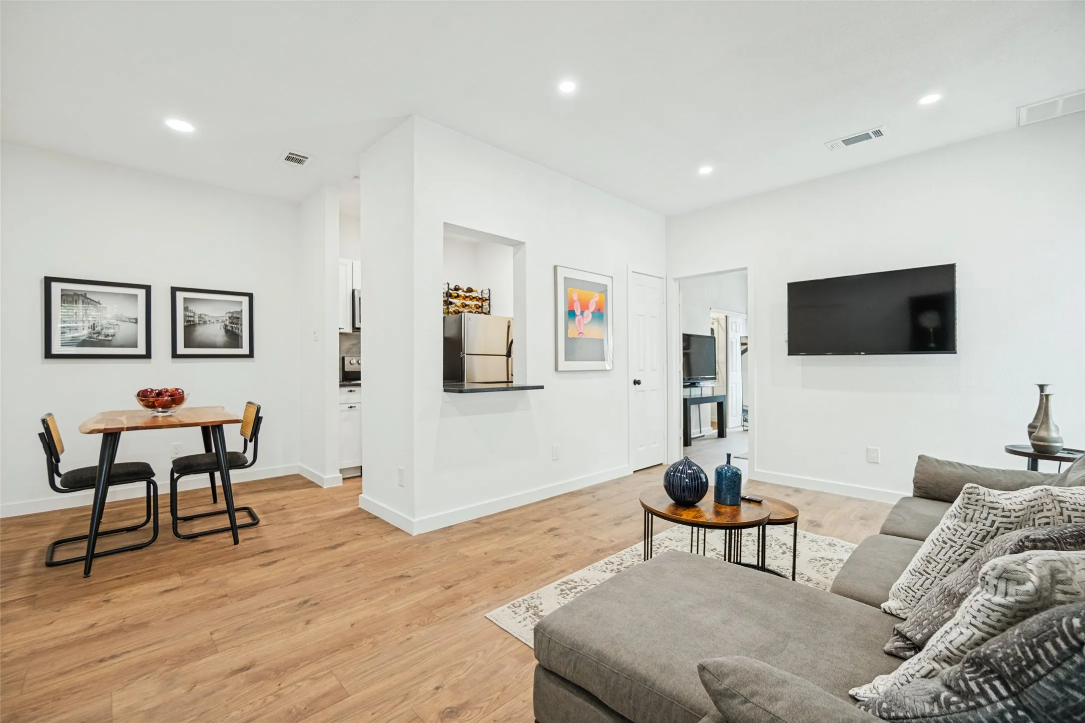 Recessed lighting, wood-finish flooring, white walls, black countertop, stainless steel refrigerator