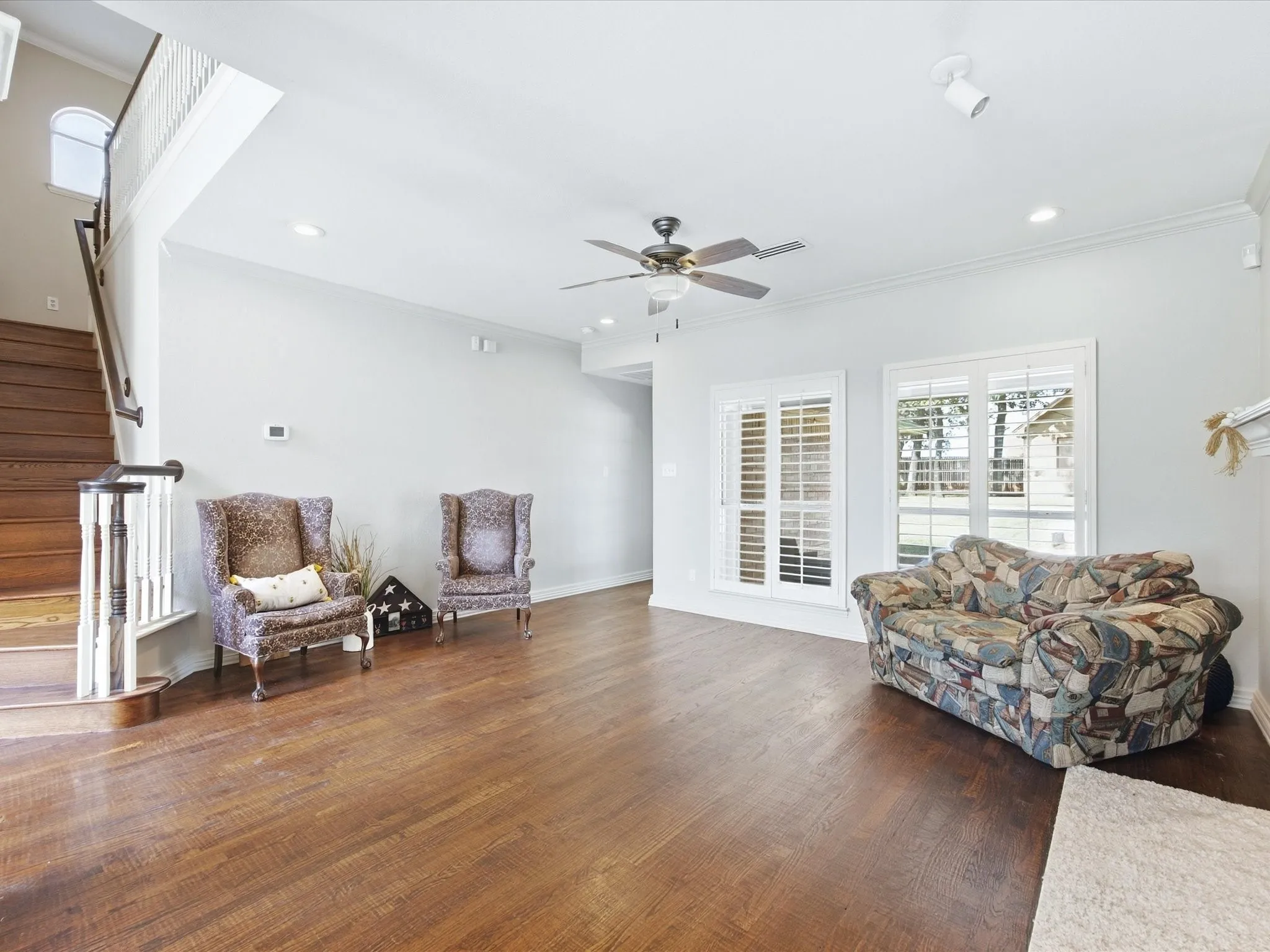Spacious room featuring wood-finish flooring, a ceiling fan, recessed lighting, and white window blinds