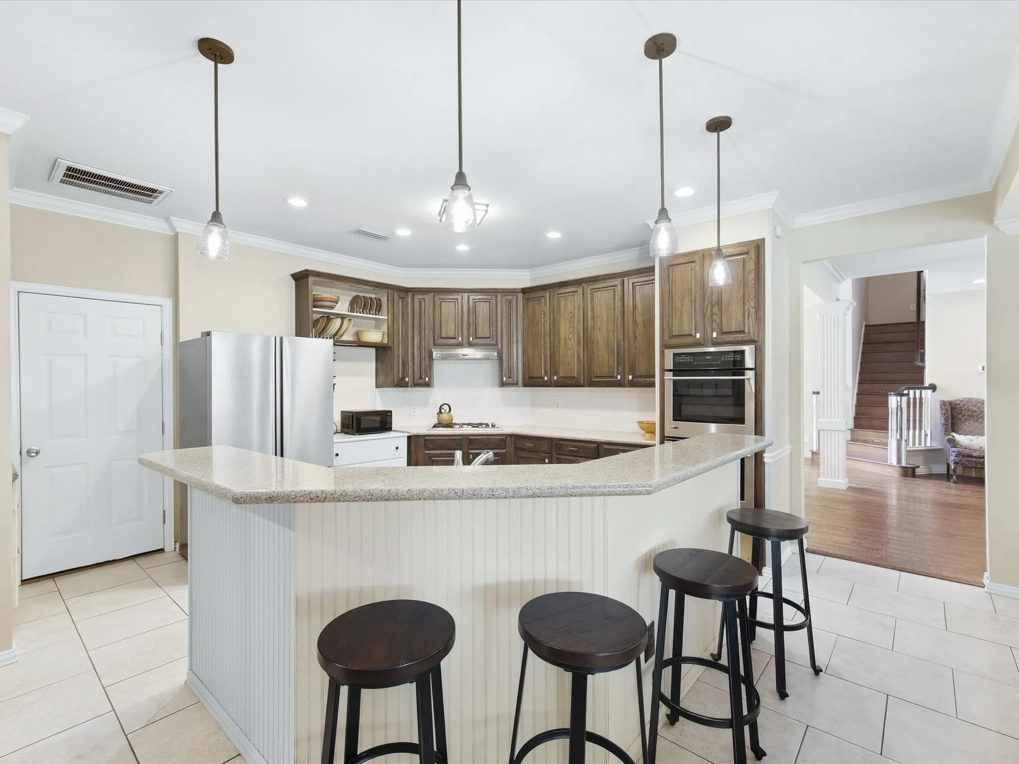 Kitchen featuring wood-finish cabinetry, light-toned countertops, tile flooring, and a built-in oven