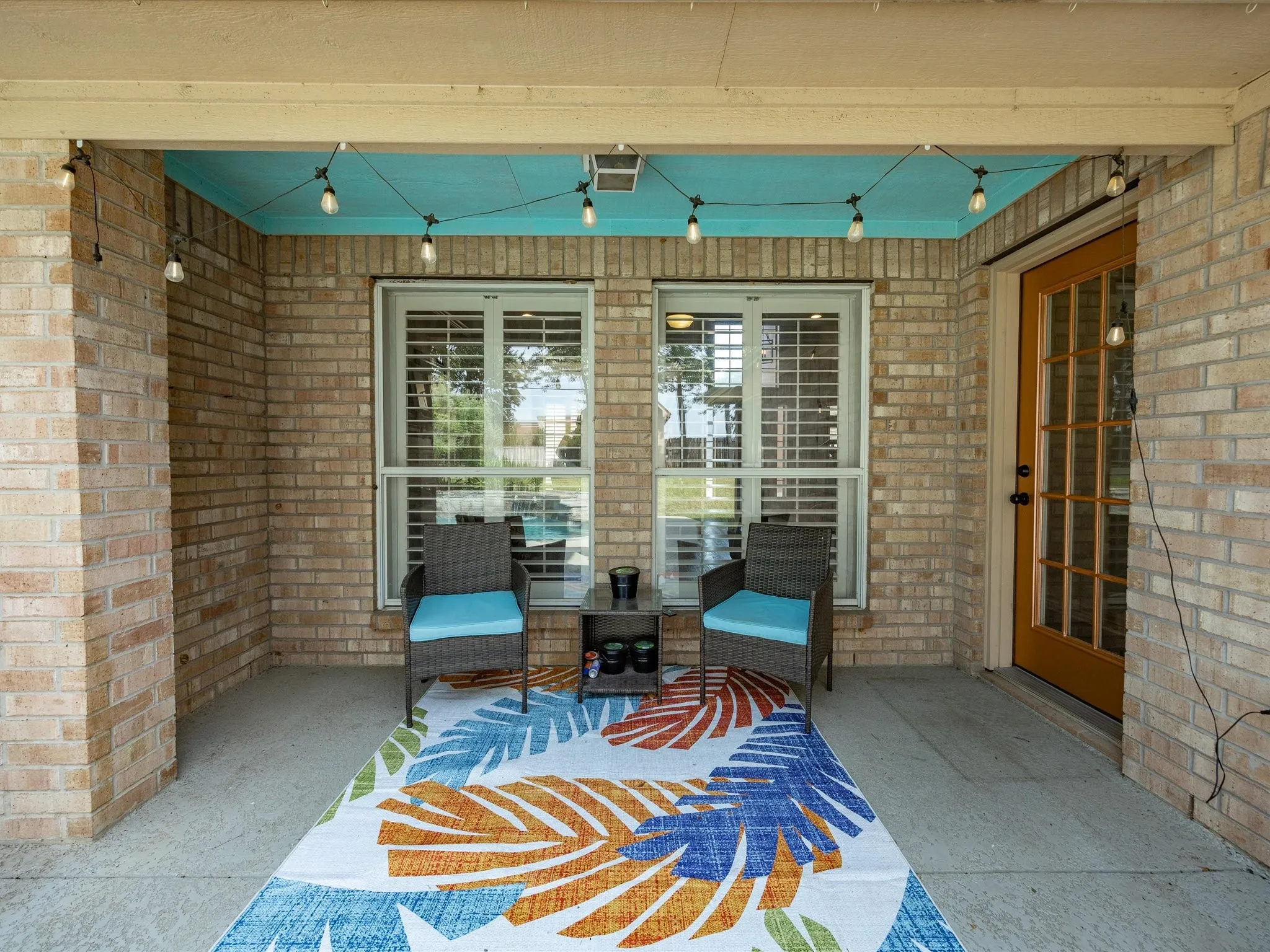Covered patio featuring a brick exterior, light blue ceiling, and a glass-paned door