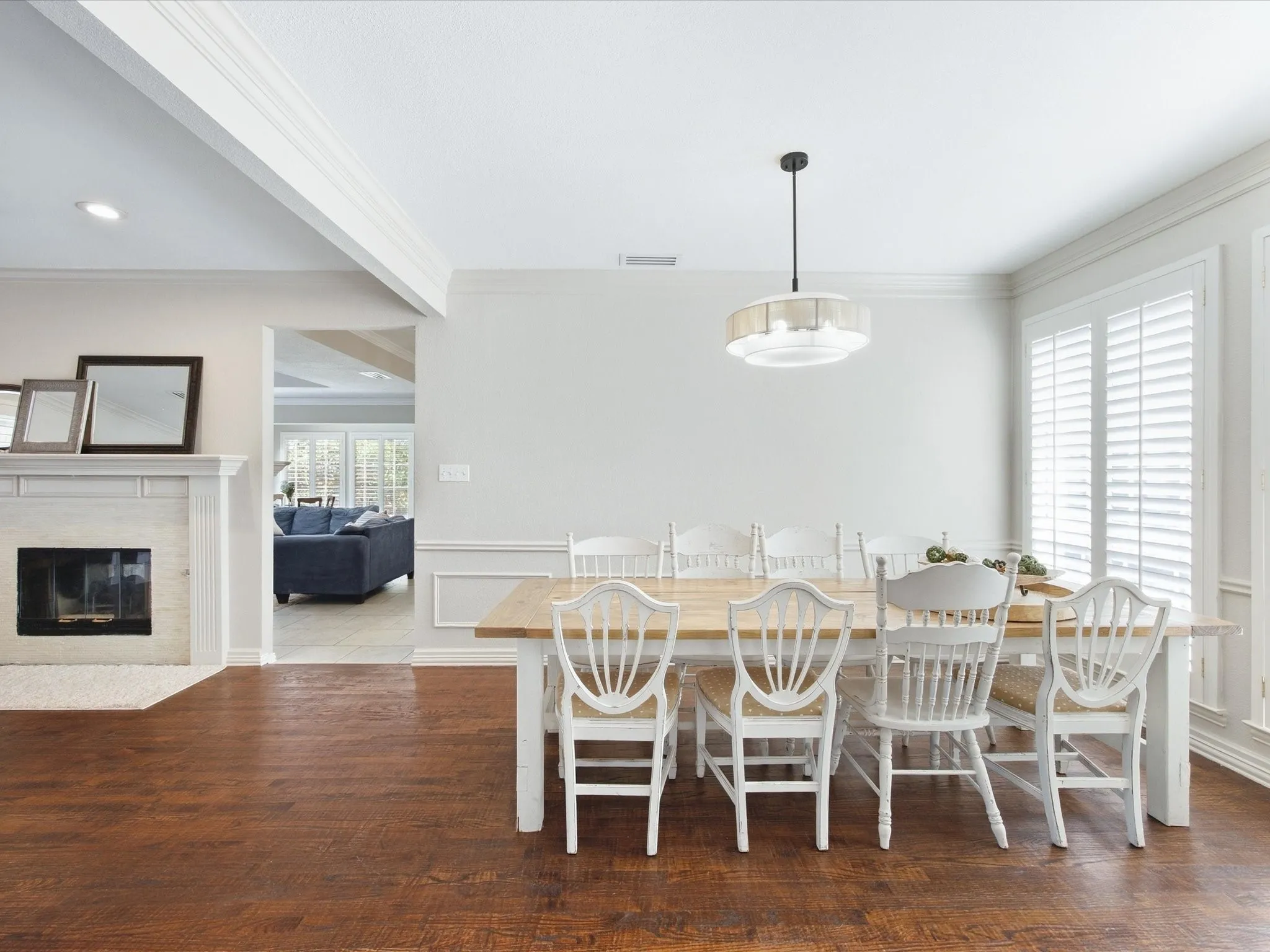 Wood-finish flooring throughout, white fireplace with mantle, and crown molding
