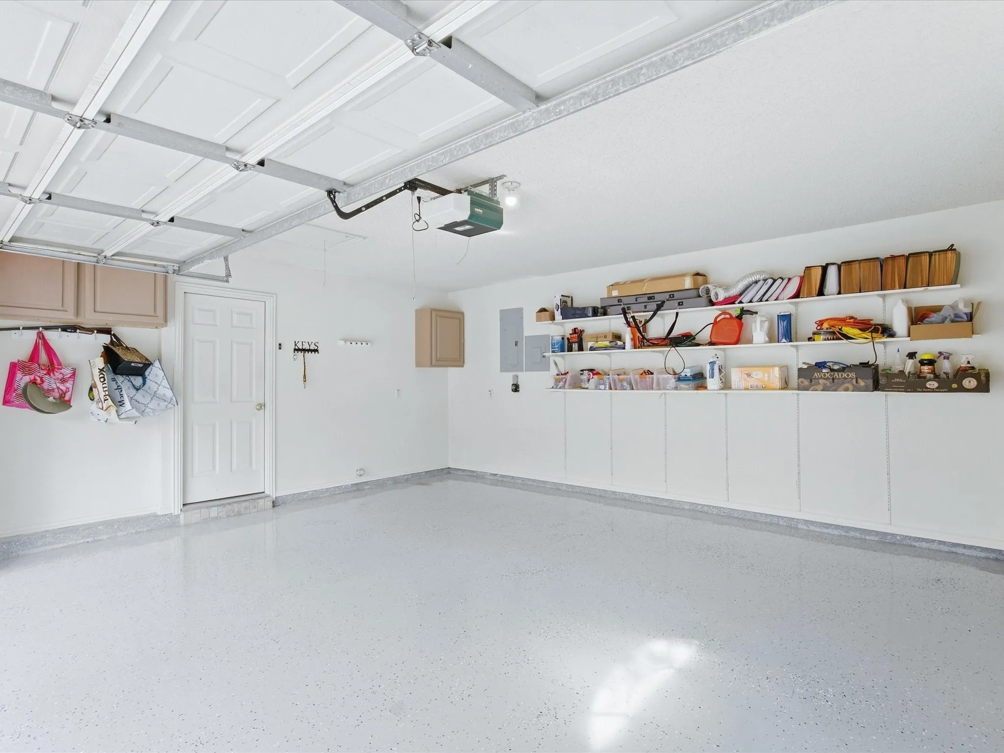 Garage featuring a light-toned epoxy floor, integrated wall shelving, built-in cabinetry, and overhead garage door opener