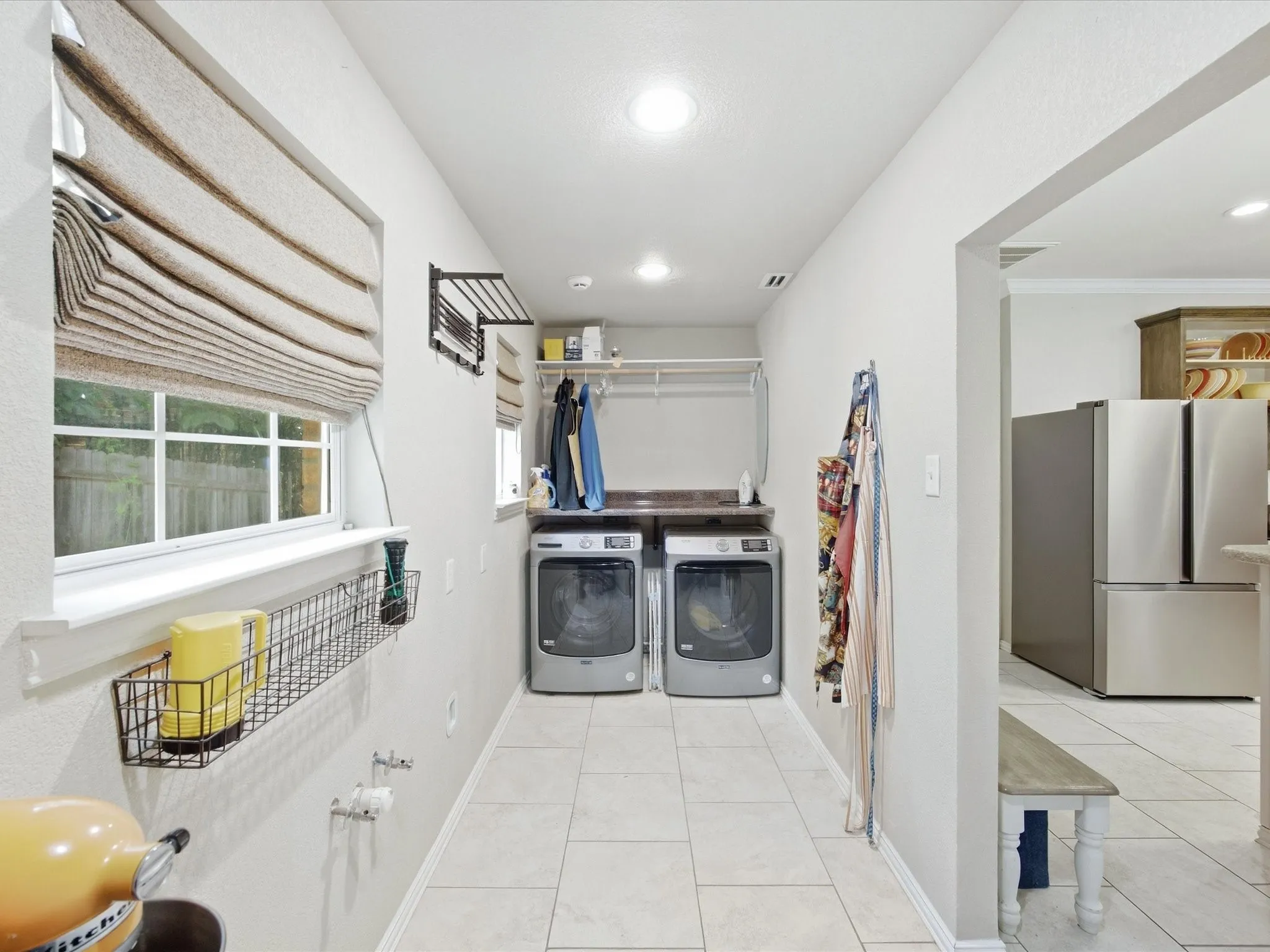 Laundry area featuring a built-in countertop, overhead shelving, and tile flooring