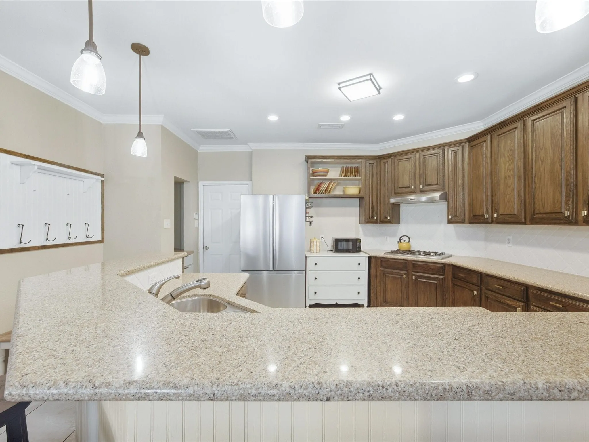 Kitchen featuring granite-style countertops, wood cabinetry, stainless steel appliances, and recessed lighting