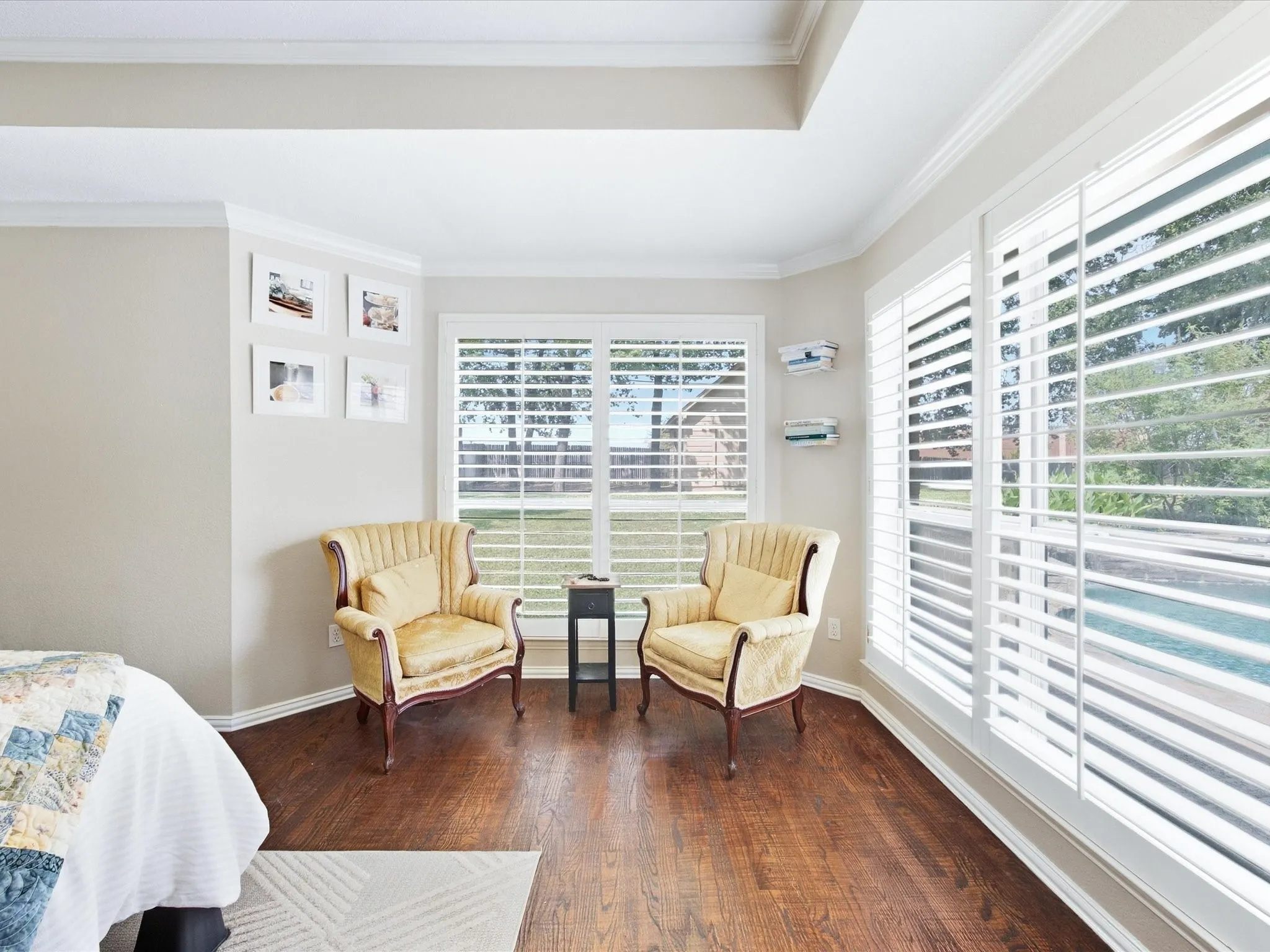 Hardwood flooring, crown molding, white plantation shutters, and multiple windows